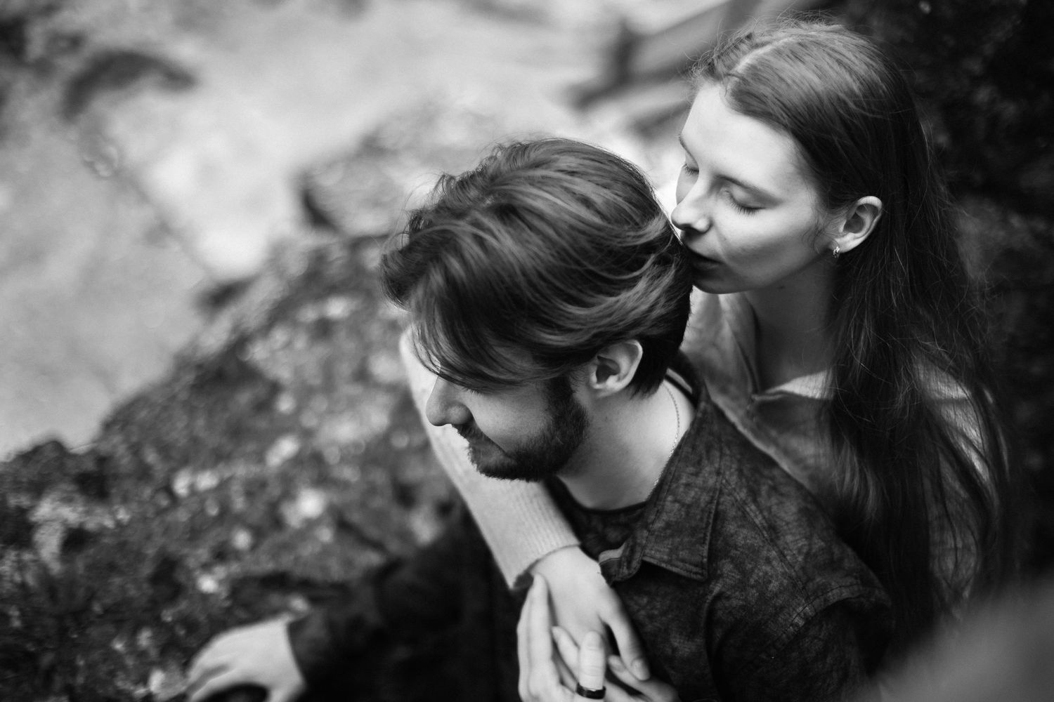 Noir & blanc d'une étreinte tendre : femme embrassant les cheveux de son homme, illustrant la profondeur du lien et la déconnexion du monde.