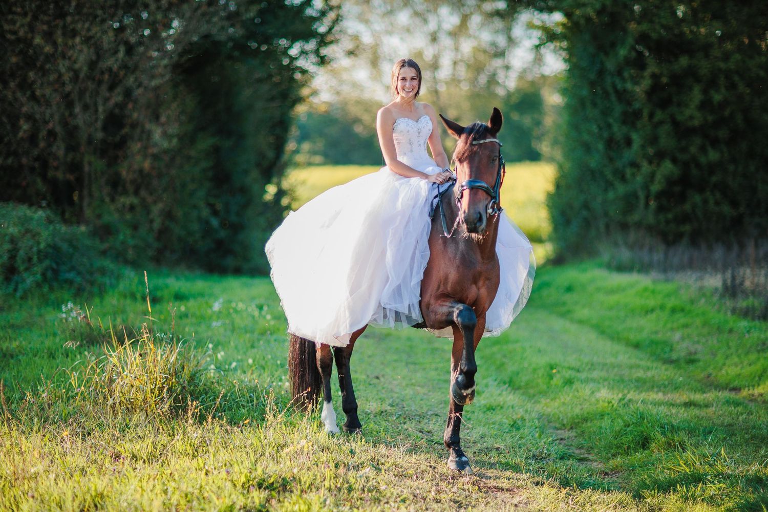Dans l'Ain, portrait complice d'une mariée et son cheval en plein jeu, photographie de mariage originale et élégante par Eric Filliat.