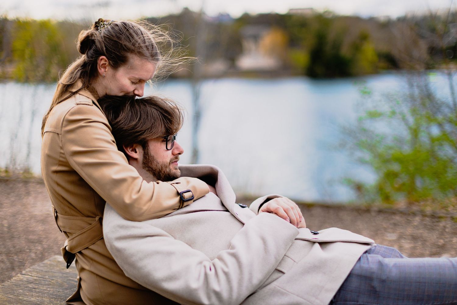 Moment de tendresse en bord de lac. Couple enlacé dans un parc lyonnais, séance engagement Lyon et périphérie.