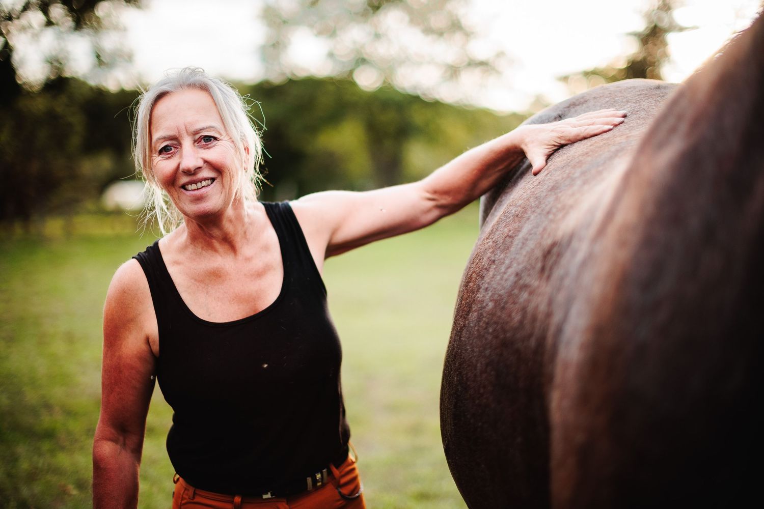 Mère caressant sa jument, regard tourné vers l'avenir. Force et douceur du lien humain-cheval, photographe animalier secteur Riom.