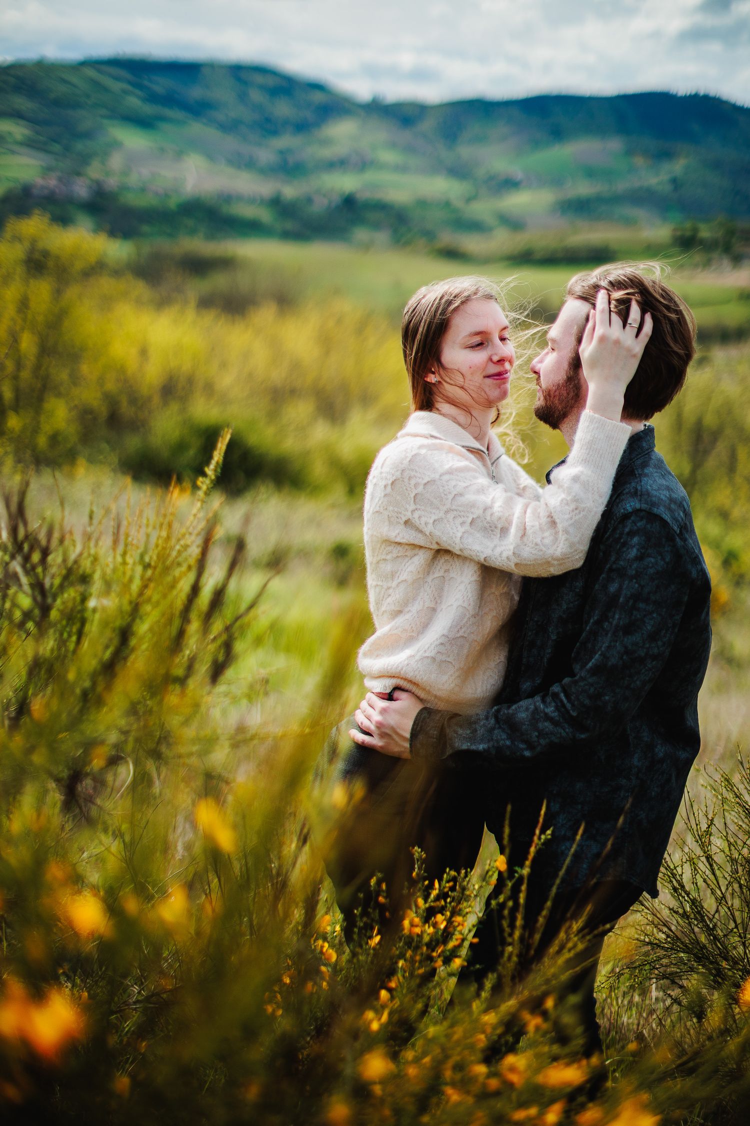 Caresse tendre et cheveux au vent dans les genêts en fleurs à Tarare par Eric Filliat, photographe de la complicité et de la famille.