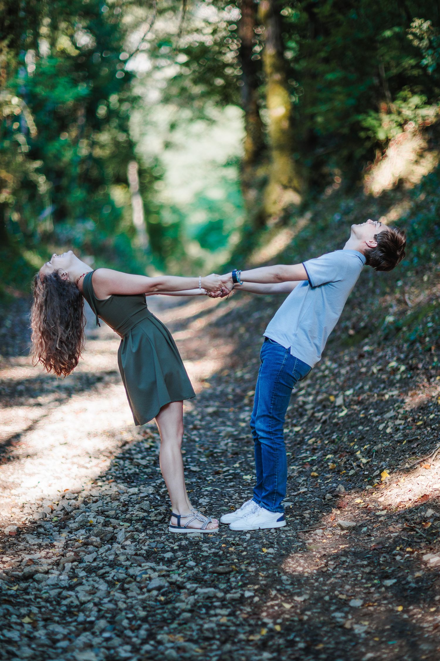 Jeunes amoureux jouant dans les bois. Équilibre et rires en extérieur, séance photo couple Auvergne et Cantal.