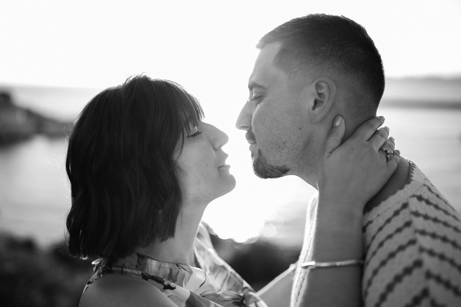 Tension d'un baiser en bord de mer au coucher du soleil. Noir et blanc artistique, photographe de couple à Marseille et en Provence.