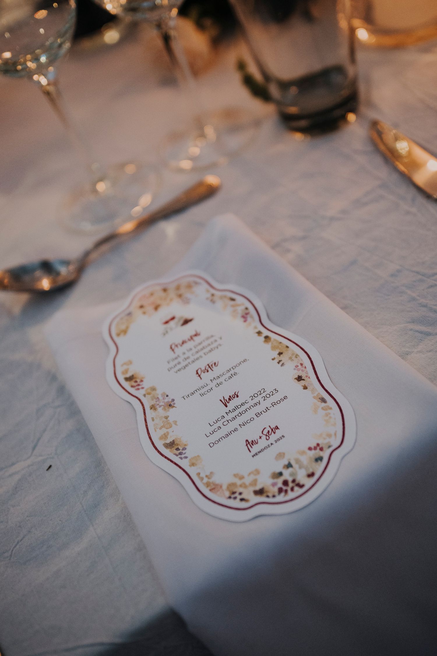 Elegant floral wedding menu card placed on white linen napkin at reception table.