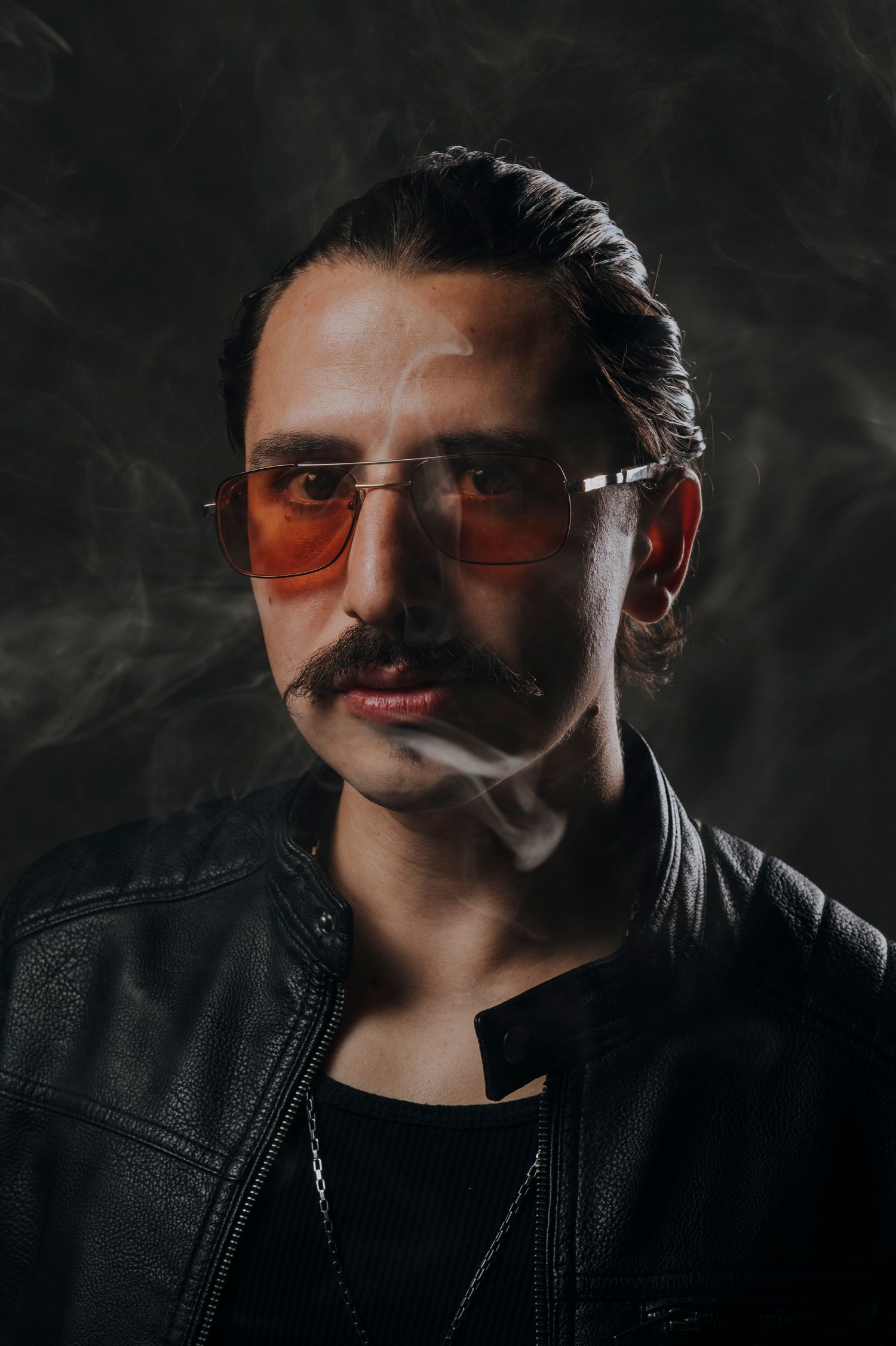 CCESCO Stylish man with mustache wearing orange tinted sunglasses and black leather jacket in smoky atmosphere.