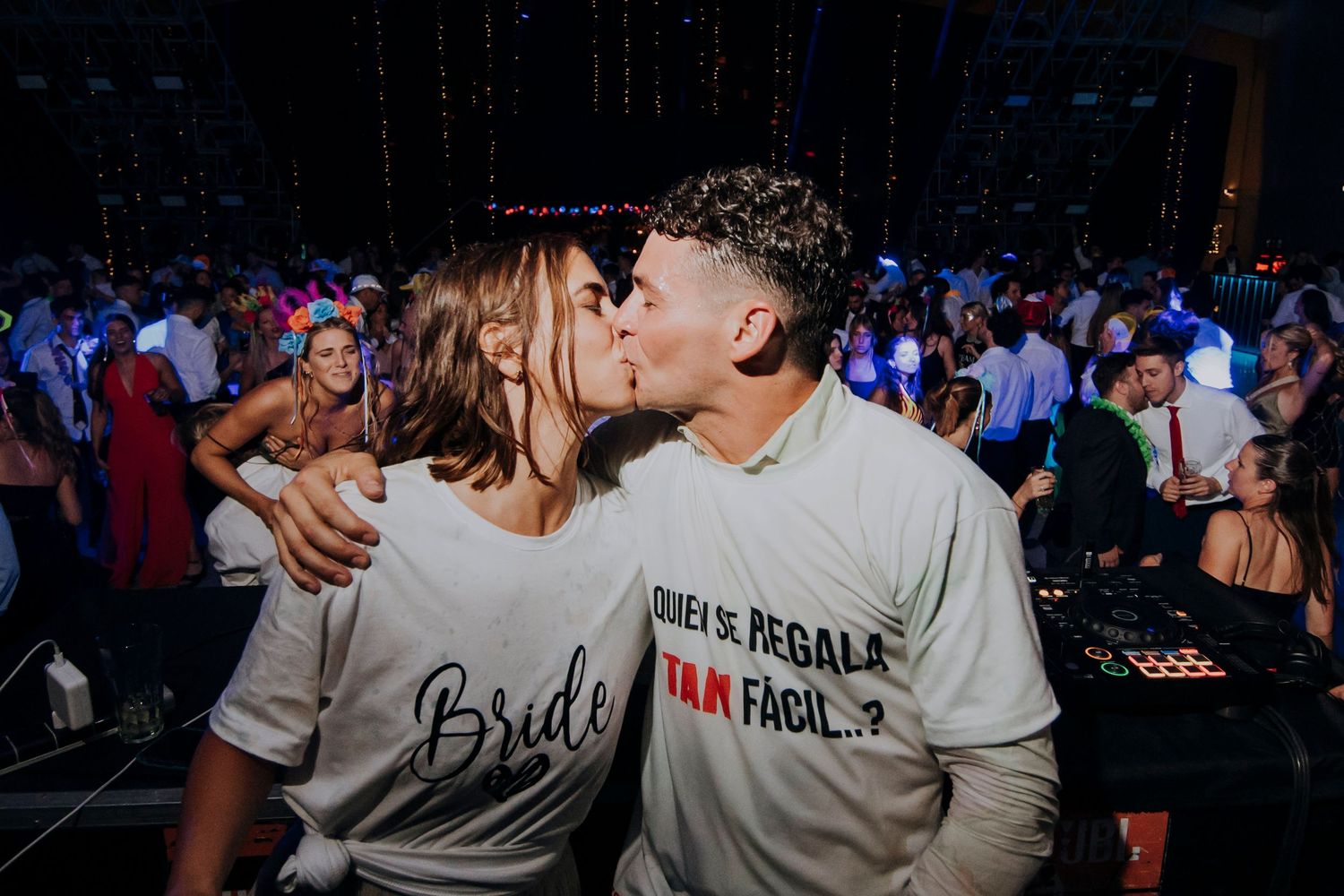 Bride and groom share a kiss on the dance floor wearing matching white t-shirts at their reception.