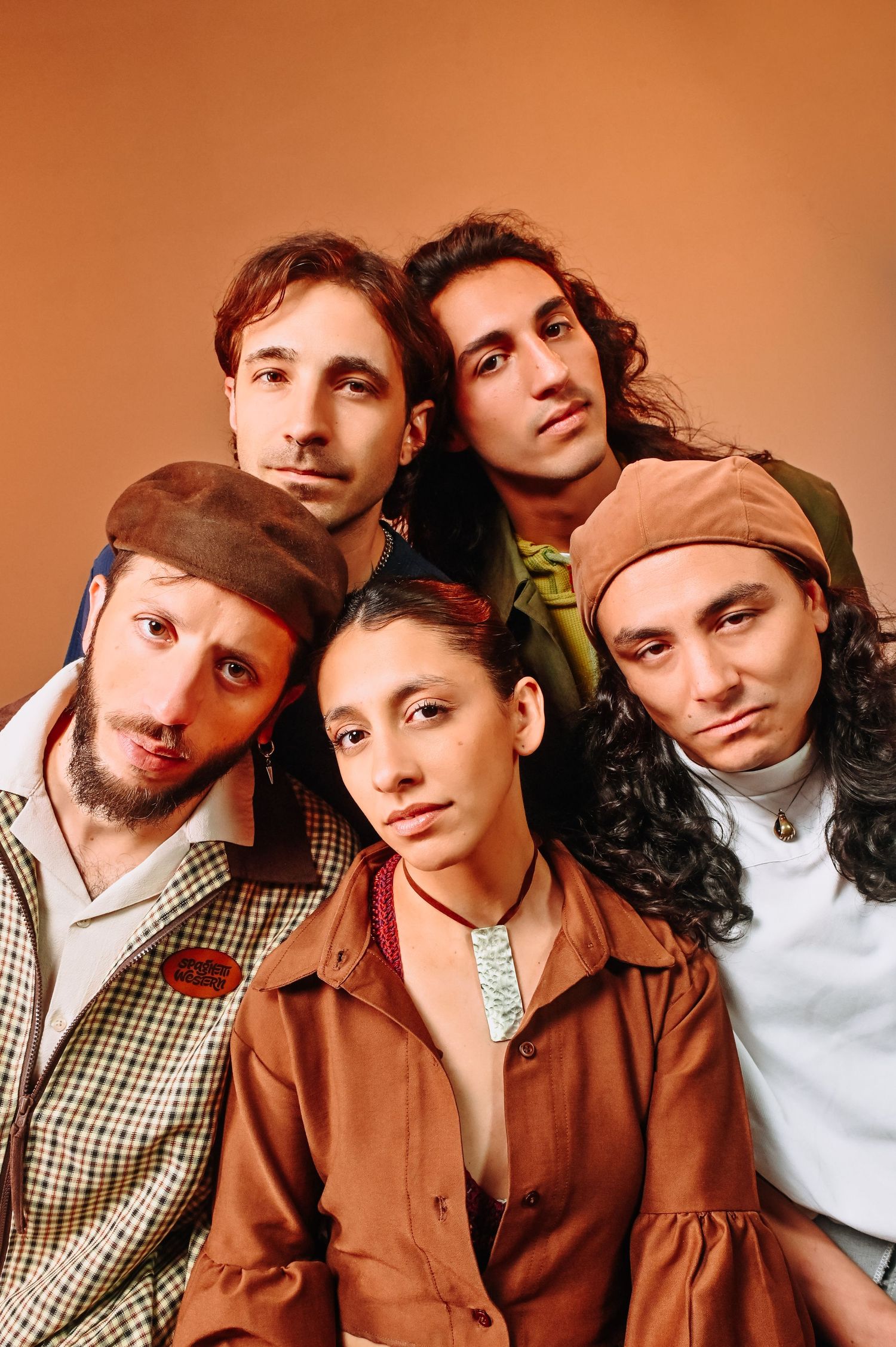 Spaghetti Western Group of five young people posing together closely against a warm brown background .