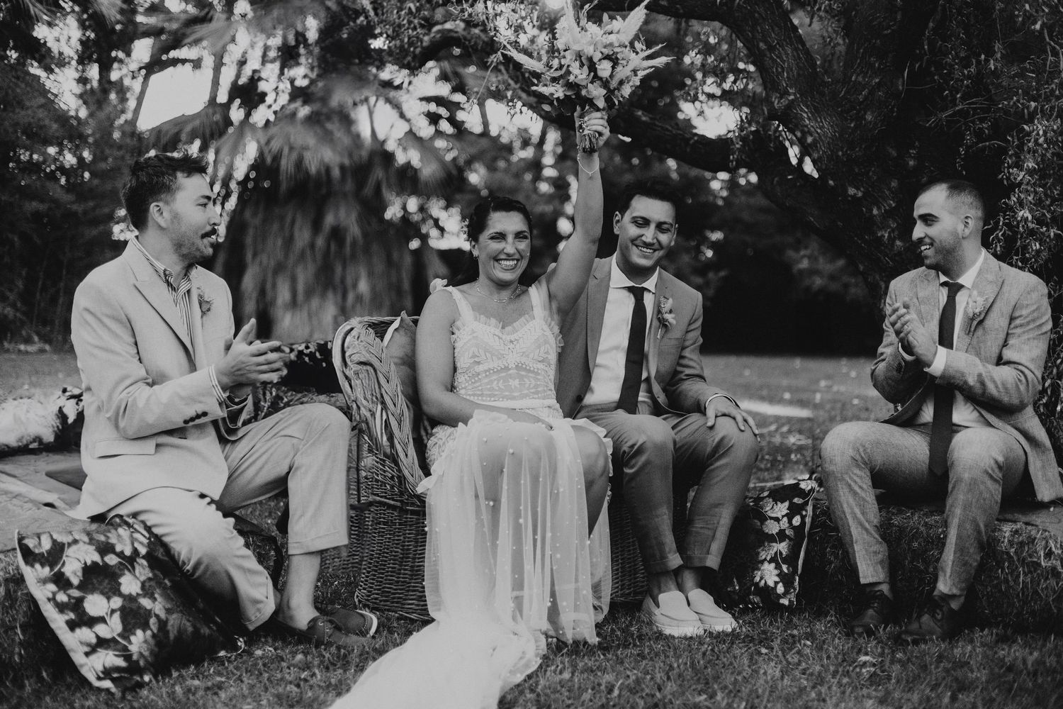 Black and white photo of bride and groom laughing with groomsmen outdoors. Emotional wedding vows in Mendoza.