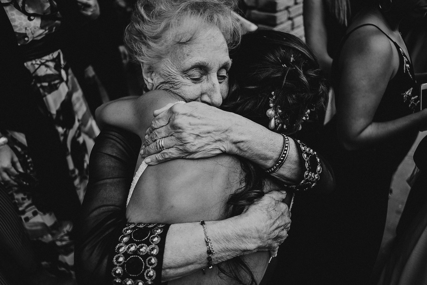Black and white photo of bride sharing a tender hug with elderly grandmotherv wedding ceremony in Mendoza, Argentina.