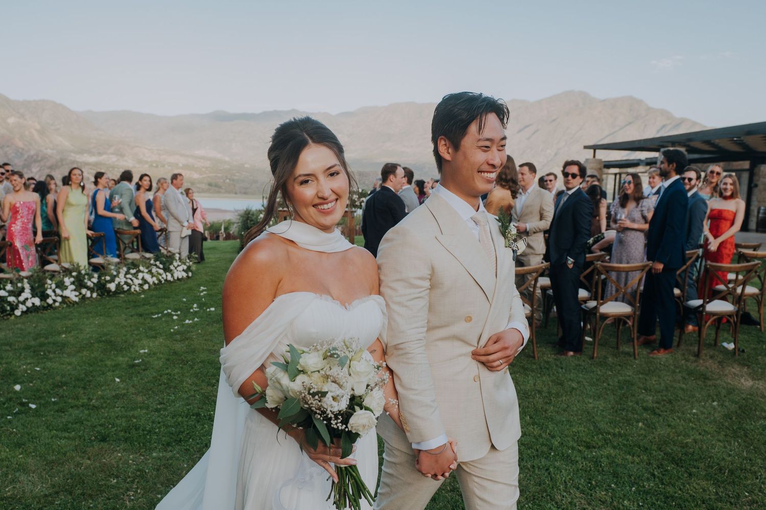 Newlyweds smiling and walking back down the aisle after outdoor mountain wedding ceremony.