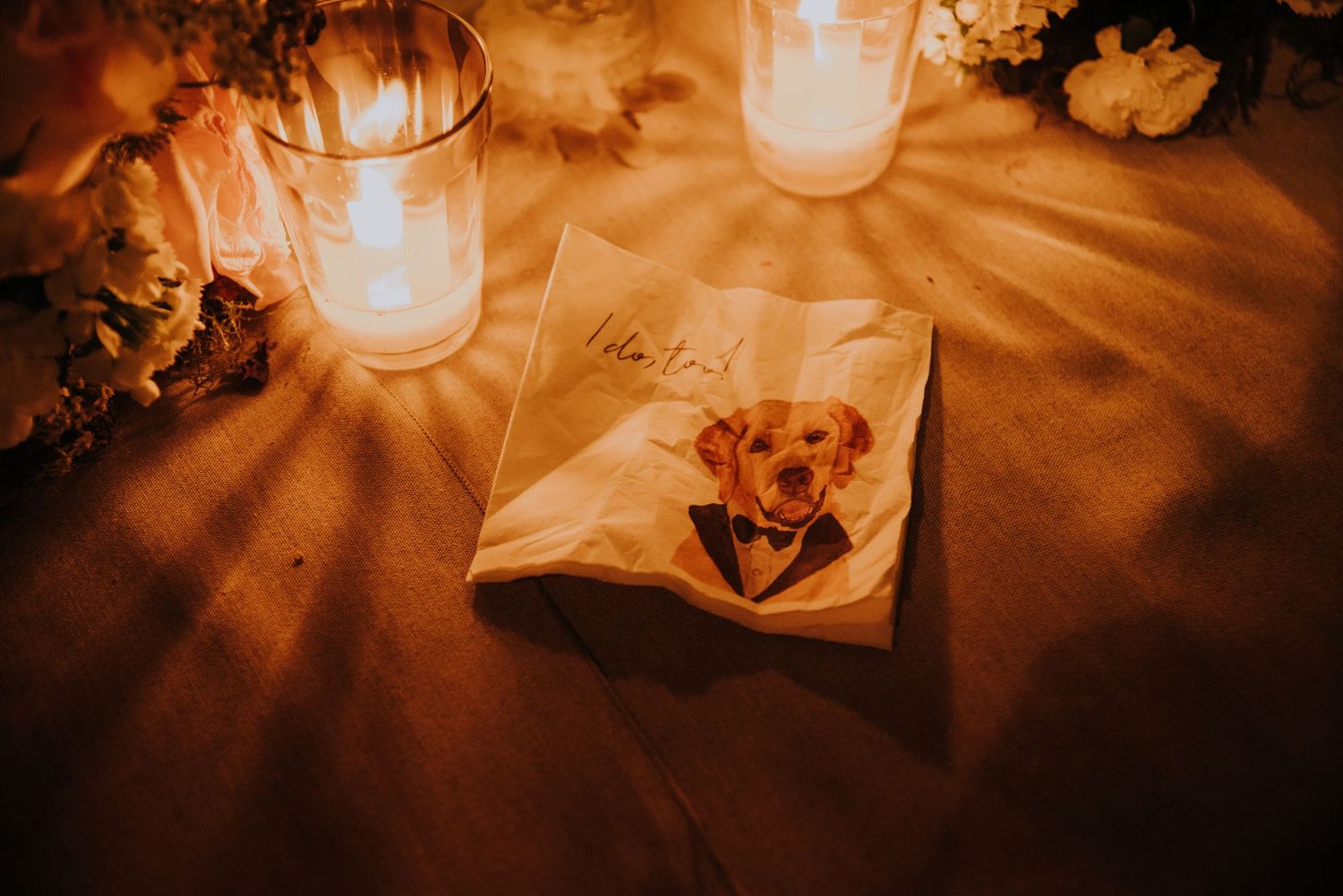 Custom wedding napkin featuring a dog in a tuxedo illustration, surrounded by glowing candles on a table.