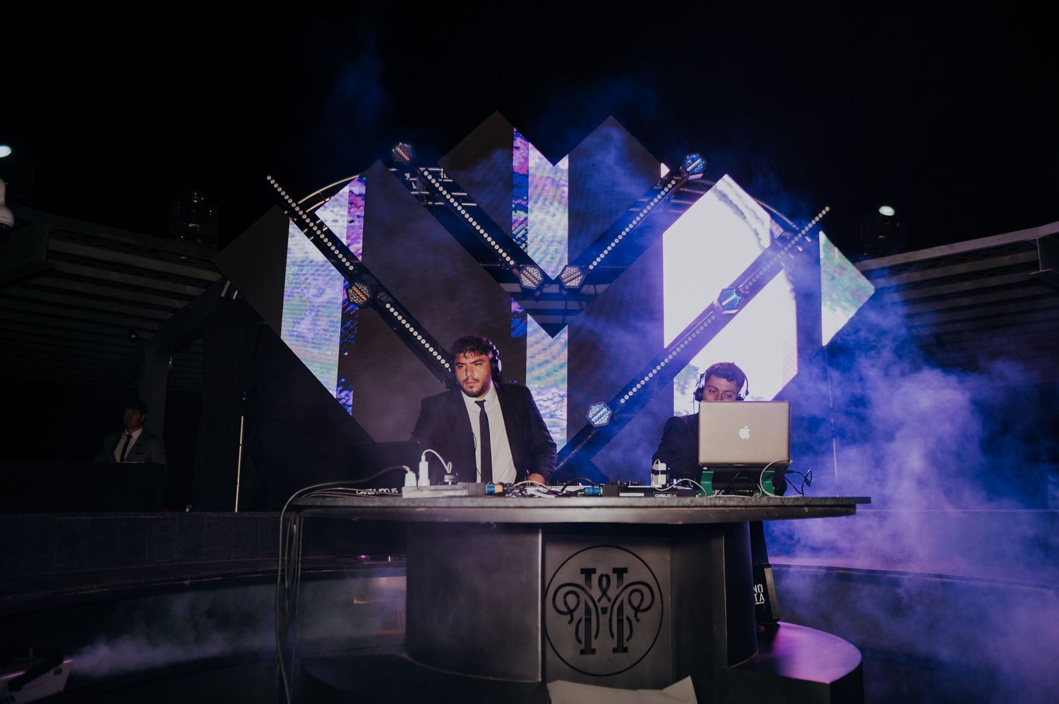 DJ performs at dramatic wedding reception with geometric light display and atmospheric fog.