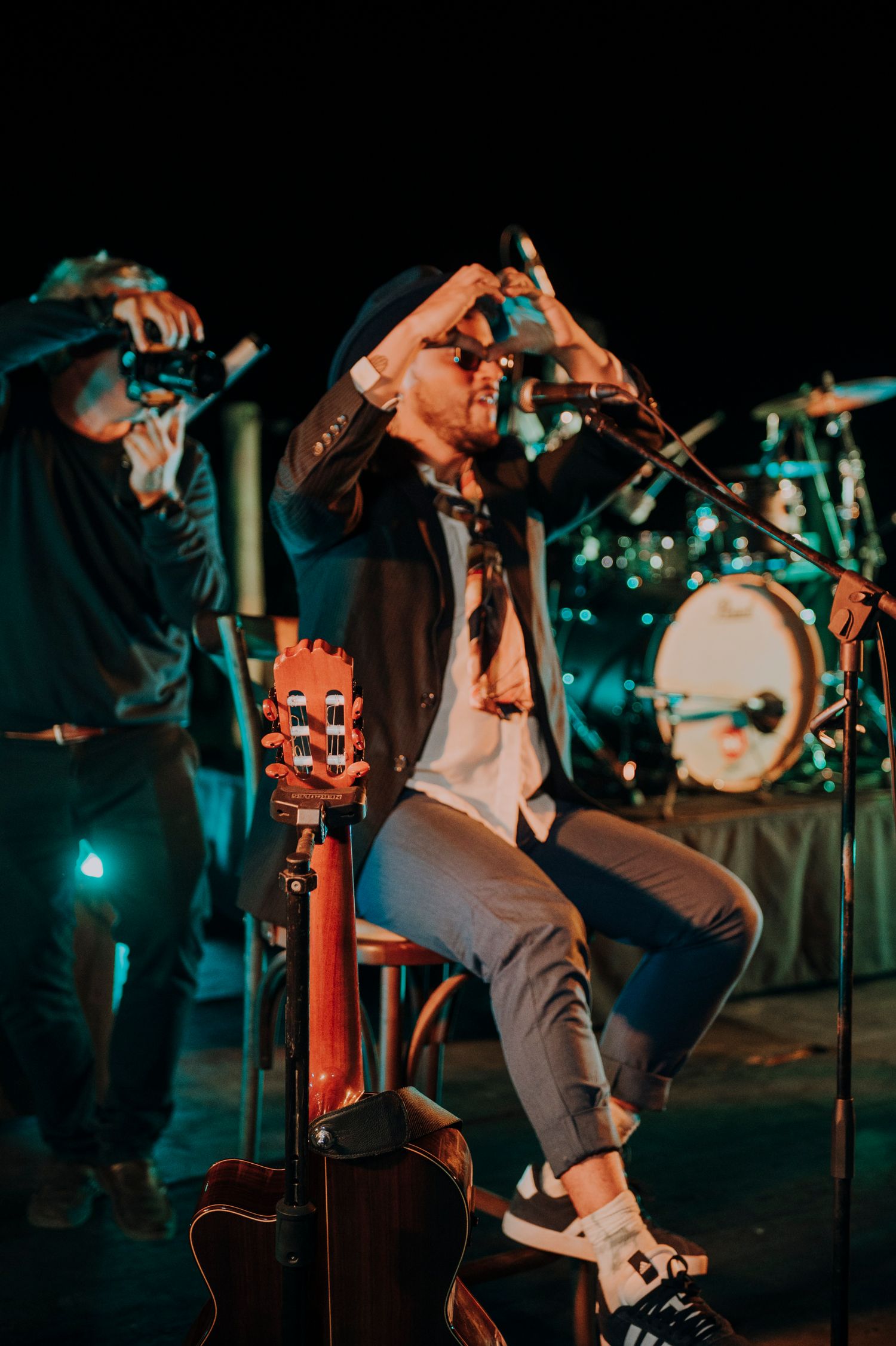 Musician performs on stage with guitar and microphone at evening wedding reception.