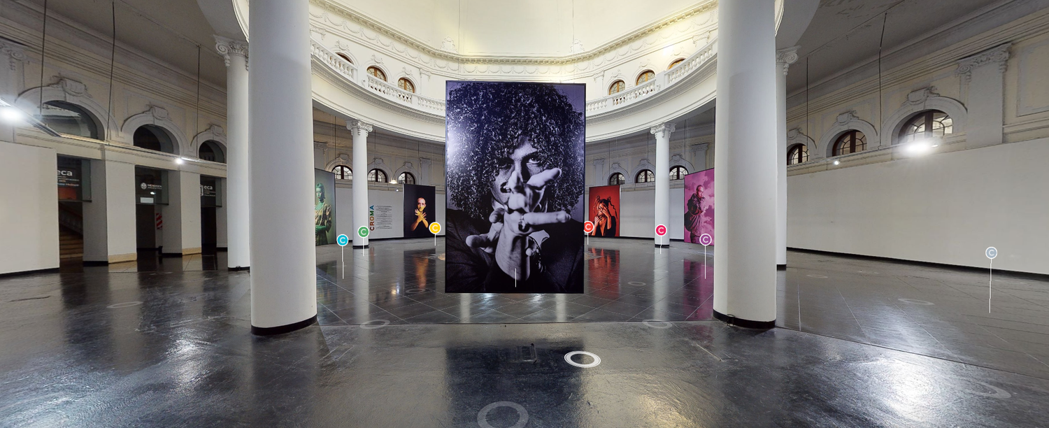 Wide view of circular art gallery hall featuring large hanging artwork installations between white columns .croma leo furio