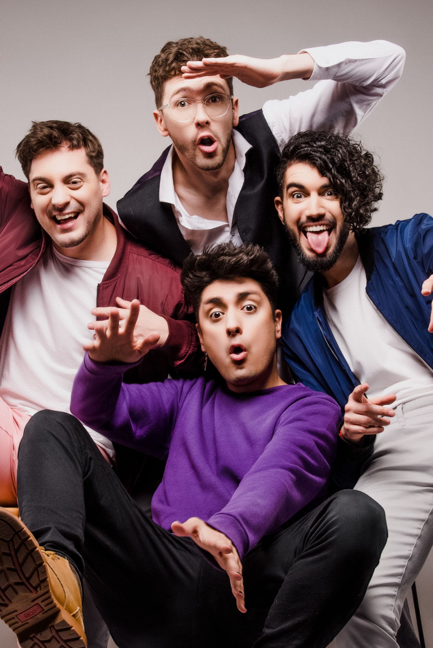 hecatombe Four young men posing playfully together against a gray studio background.