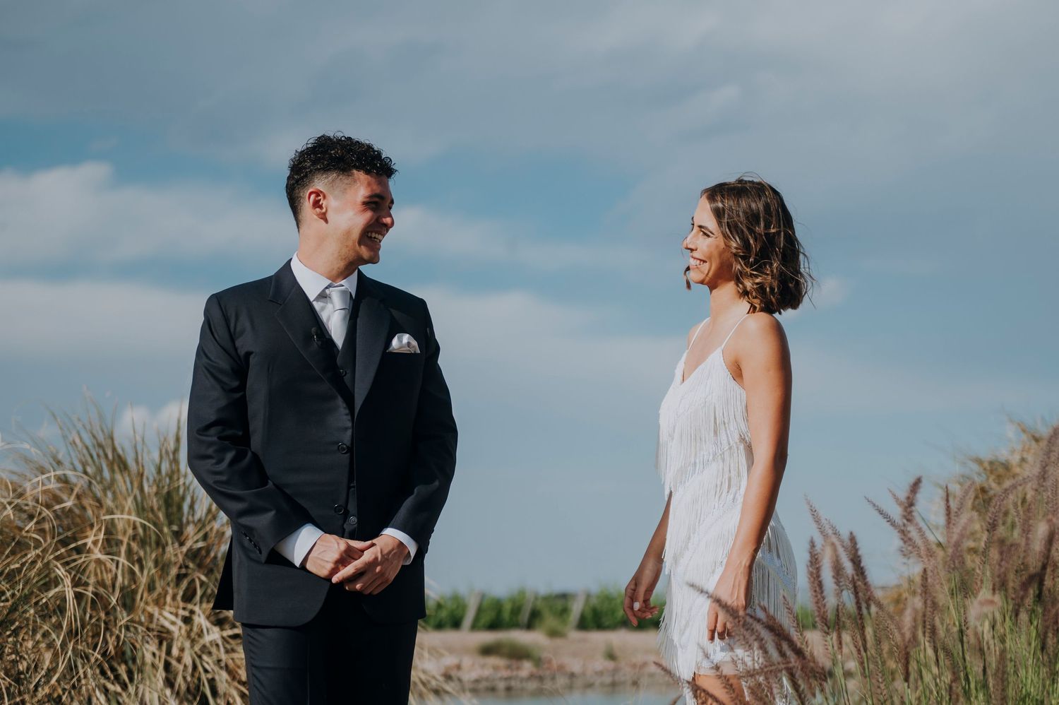 Bride and groom share a joyful moment together in a scenic outdoor setting with dramatic cloudy skies.