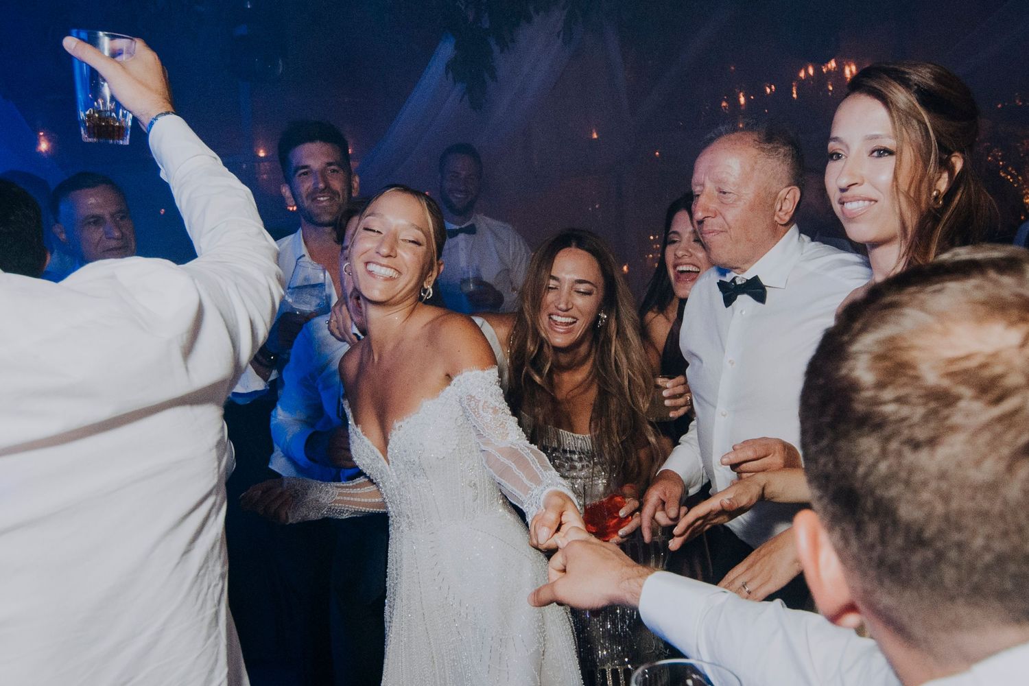 Bride and guests celebrate joyfully on dance floor at lively wedding reception.