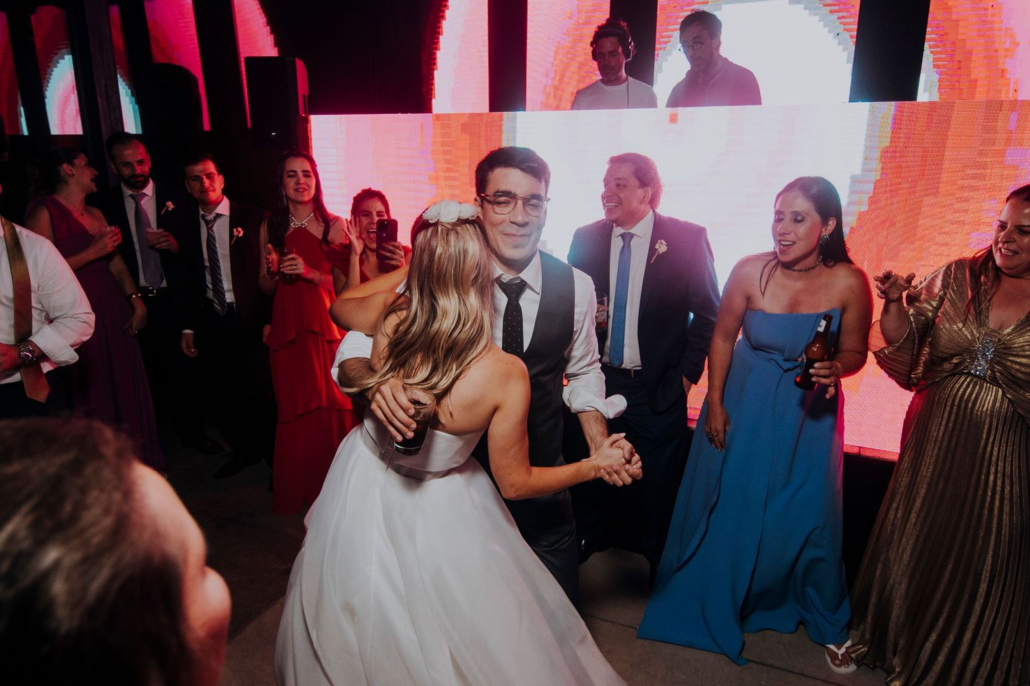 Bride and groom sharing their first dance surrounded by cheering guests on a vibrant dance floor.