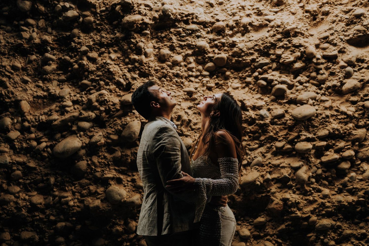 Couple sharing intimate moment leaning against rustic stone wall outdoors in vineyard mendoza