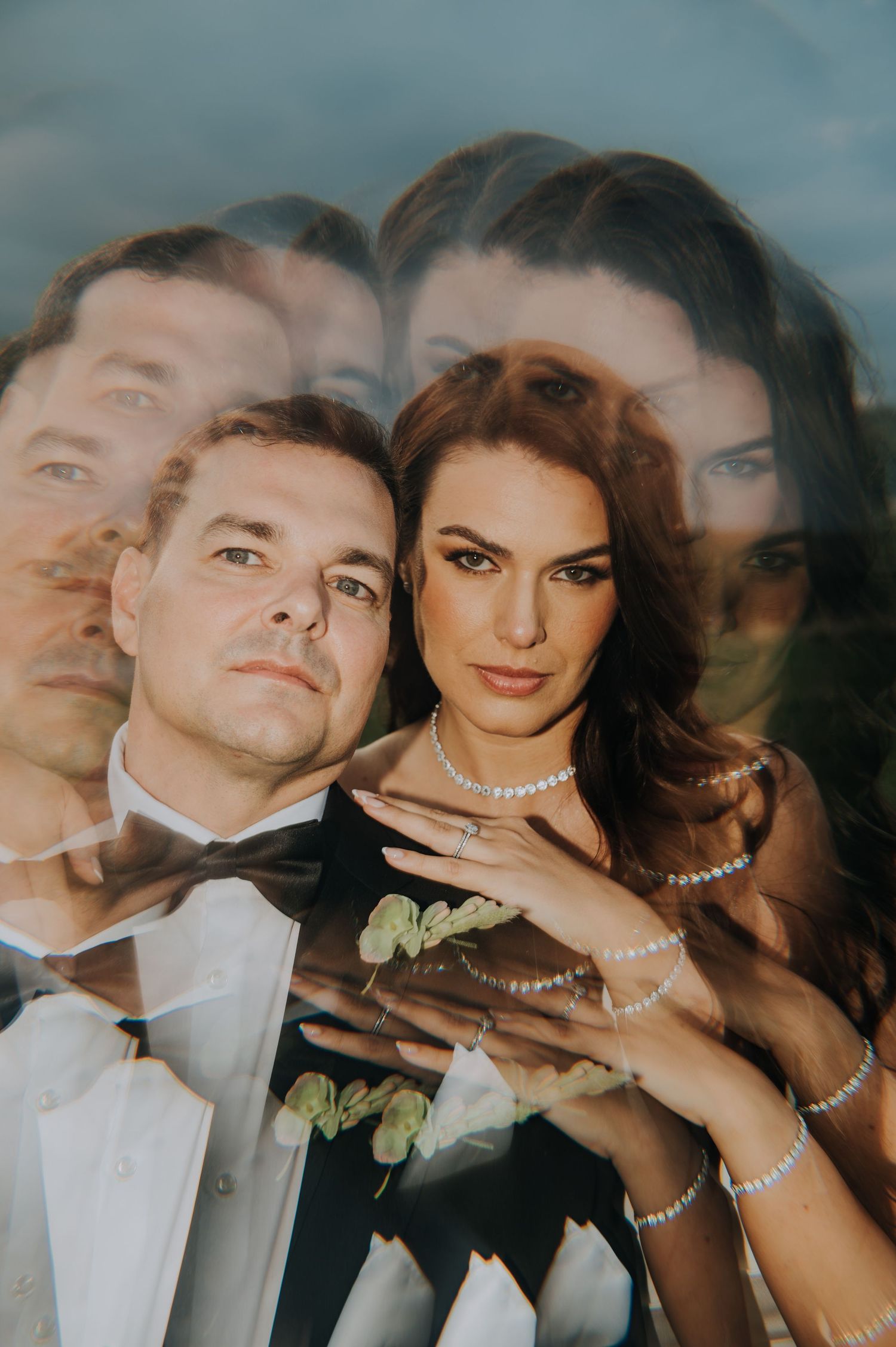 Double exposure wedding portrait of bride and groom in elegant attire creating dreamy layered effect.
