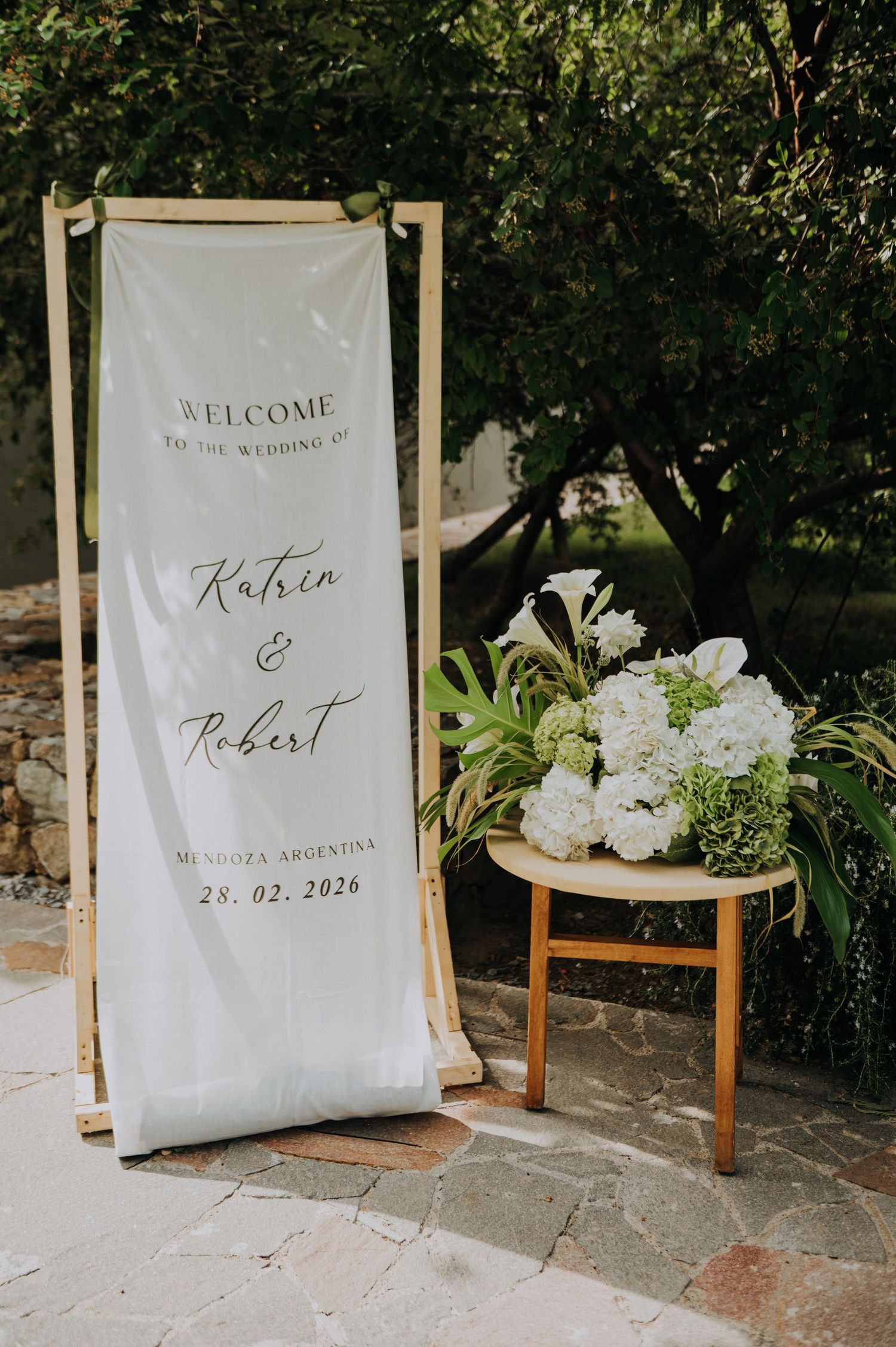 Welcome wedding sign for Katrin and Robert, Mendoza Argentina, February 28 2026, with white floral arrangement.