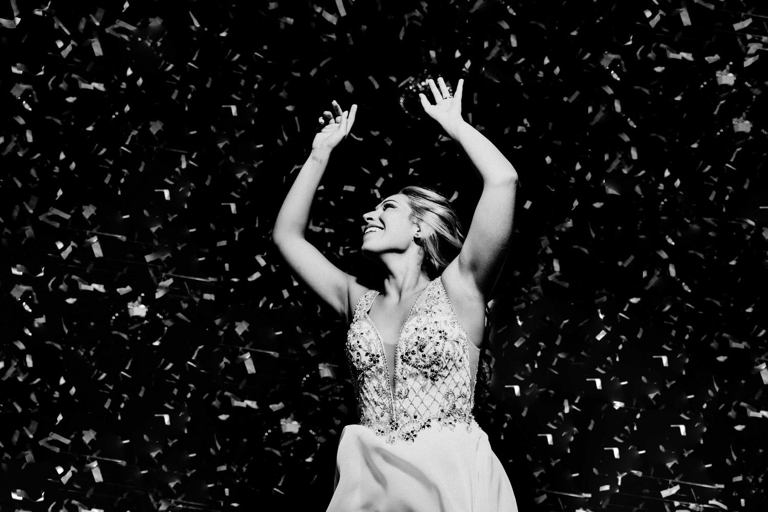Black and white photo of bride dancing joyfully in falling confetti at reception.wedding cparty in Mendoza, Argentina.