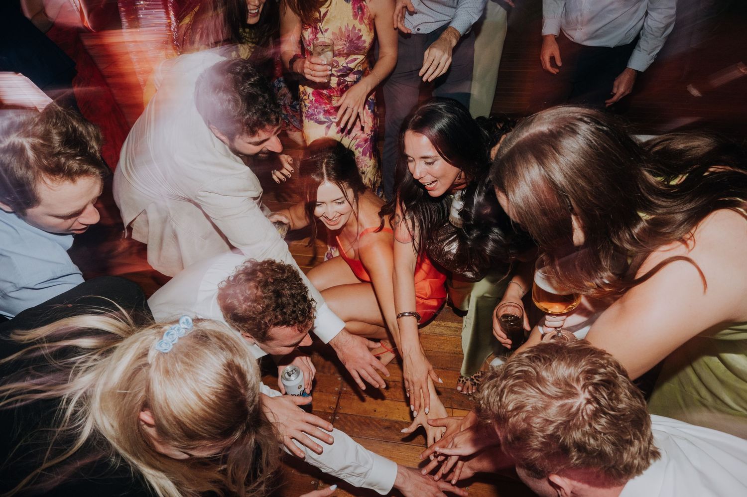 Wedding guests gathered in a circle on the dance floor joining hands together during the reception.