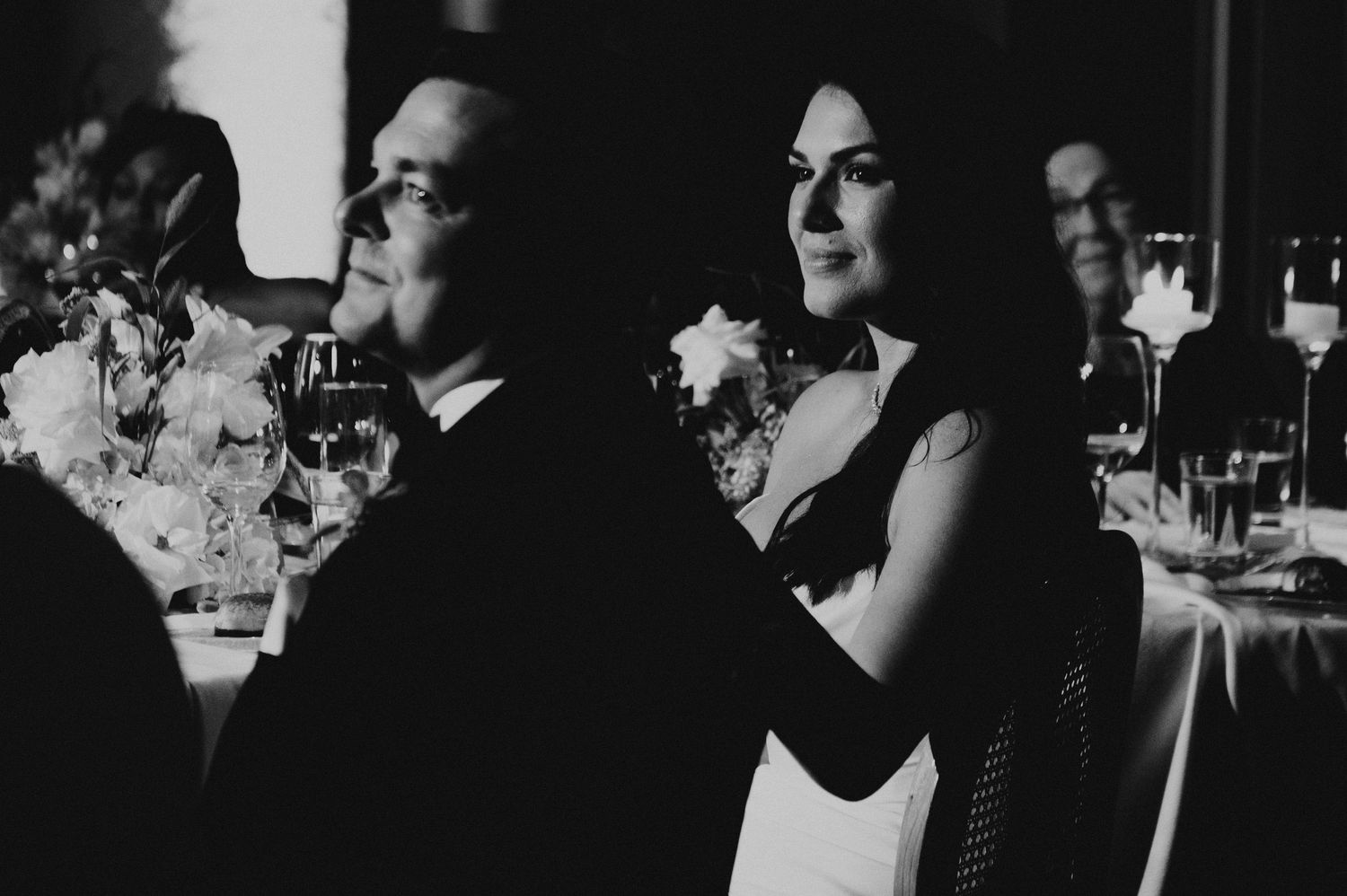 Elegant couple shares a tender moment at a wedding reception in black and white photo.
