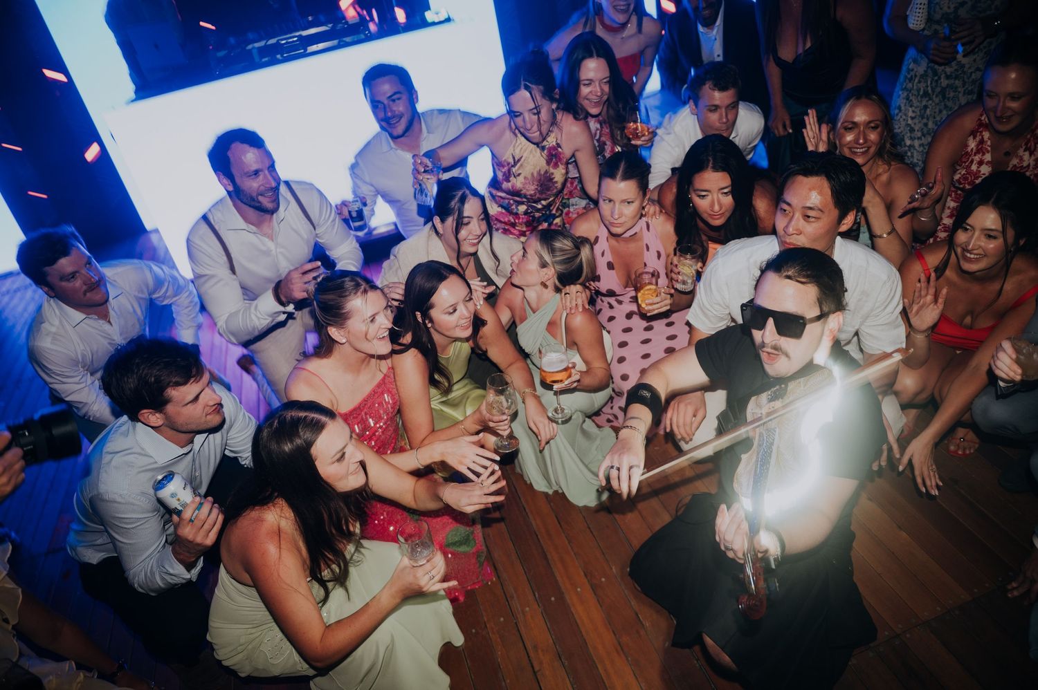 Guests celebrating at a lively wedding reception party, dancing and taking selfies on the dance floor.