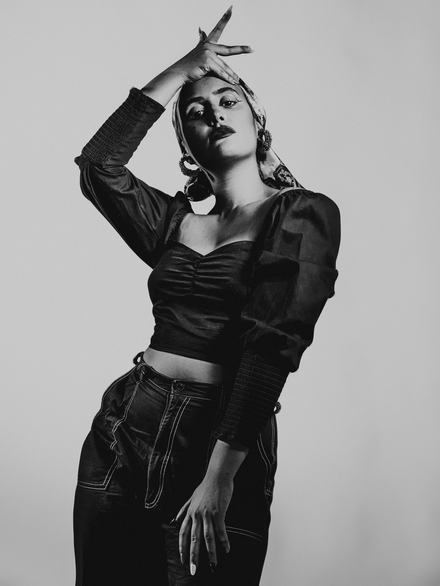 la valenti Black and white fashion portrait of a woman in crop top and jeans striking a dramatic pose.