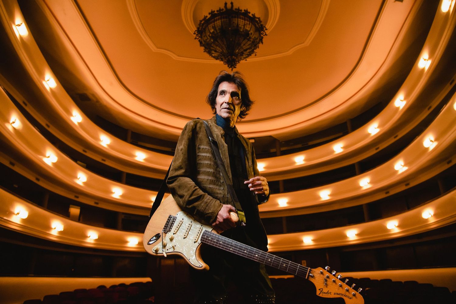 FELIPE STAITI Musician holding a Fender Stratocaster guitar on stage inside a grand ornate theater.