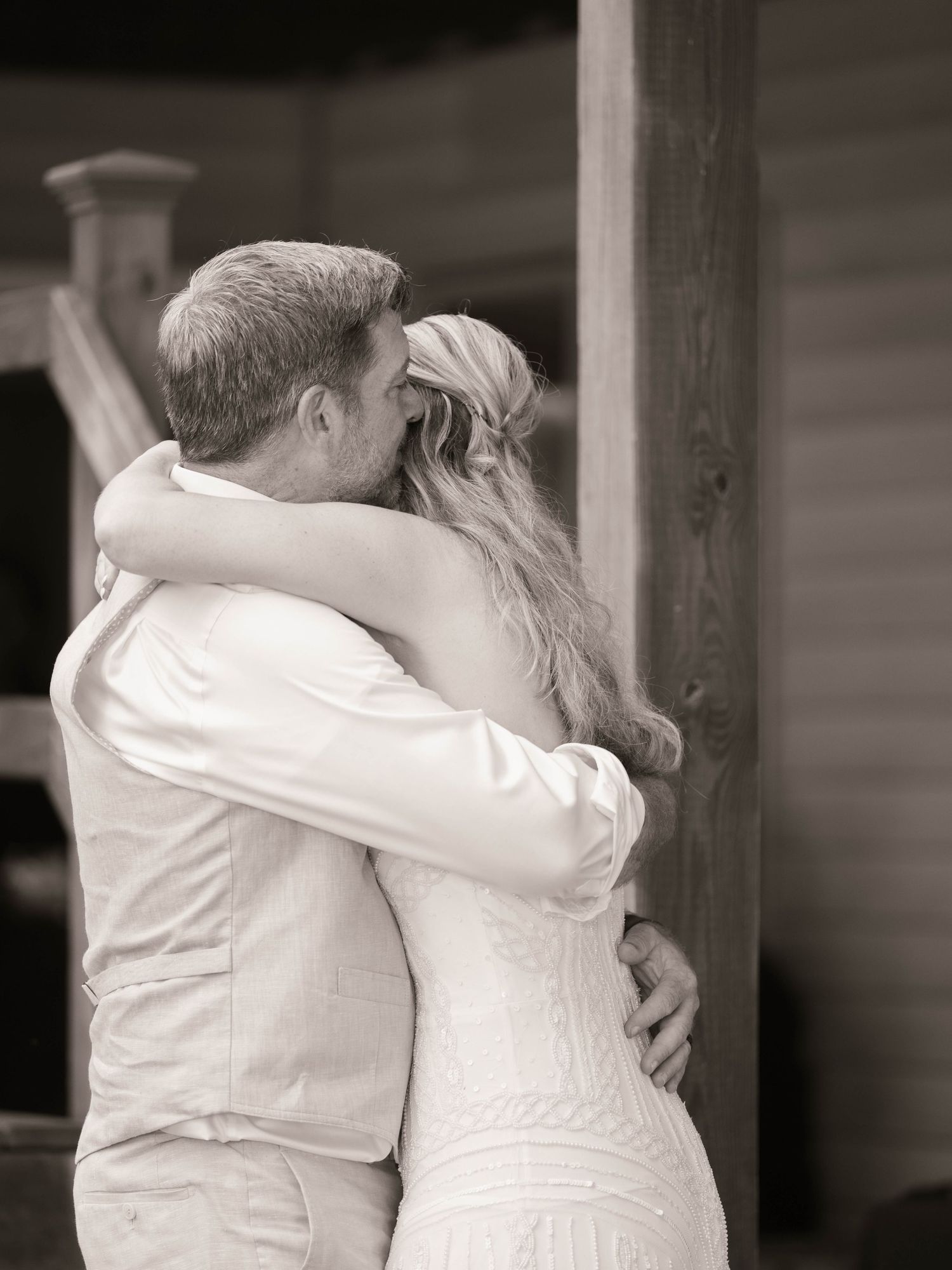 Black and white photo of a bride and groom sharing a tender embrace on their wedding day.