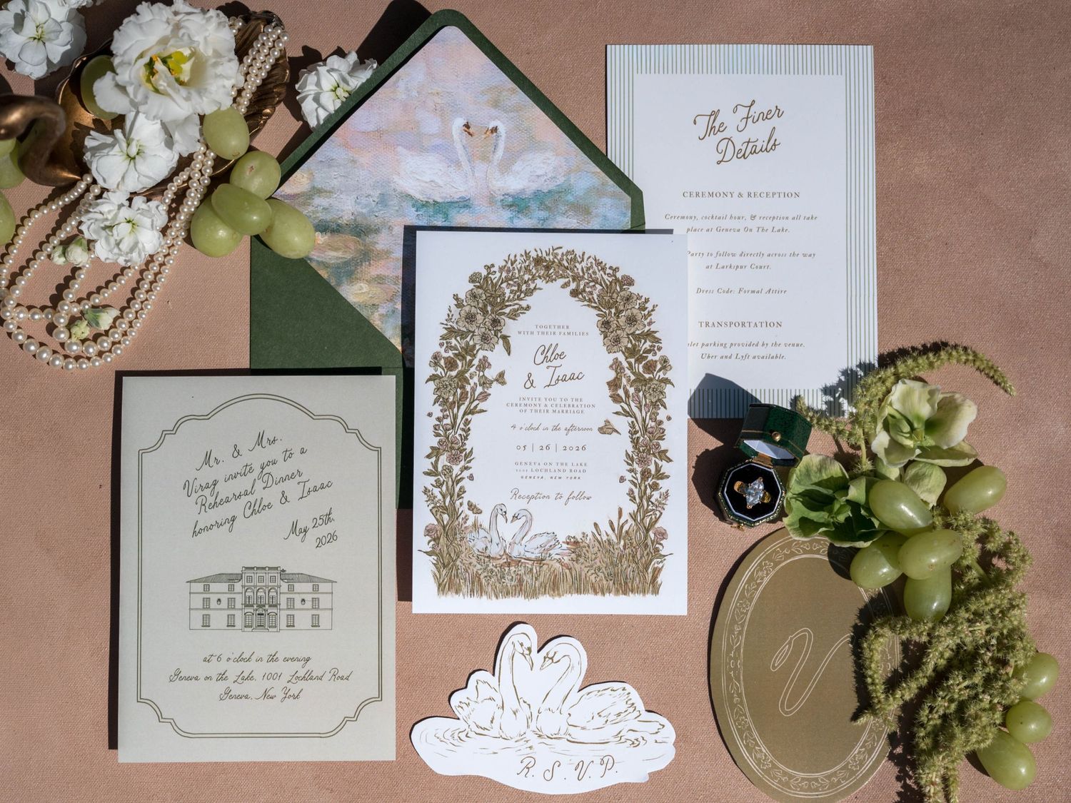 Wedding stationery suite with swan motif, green envelope, pearl necklace, and floral accents on pink background.
