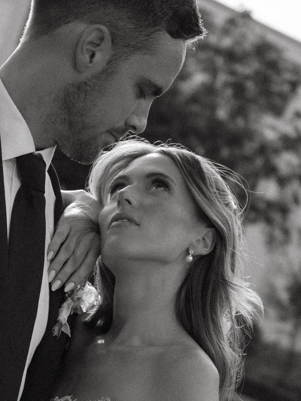 Intimate black and white portrait of bride and groom gazing at each other in tender wedding moment.