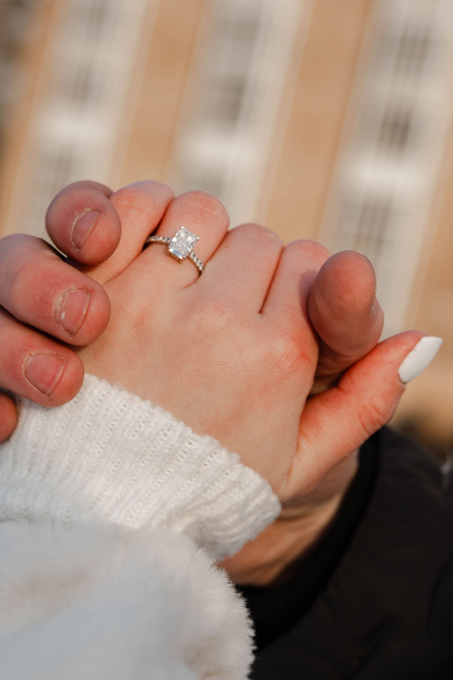 Close-up of engaged couples hands showing a princess-cut diamond engagement ring.