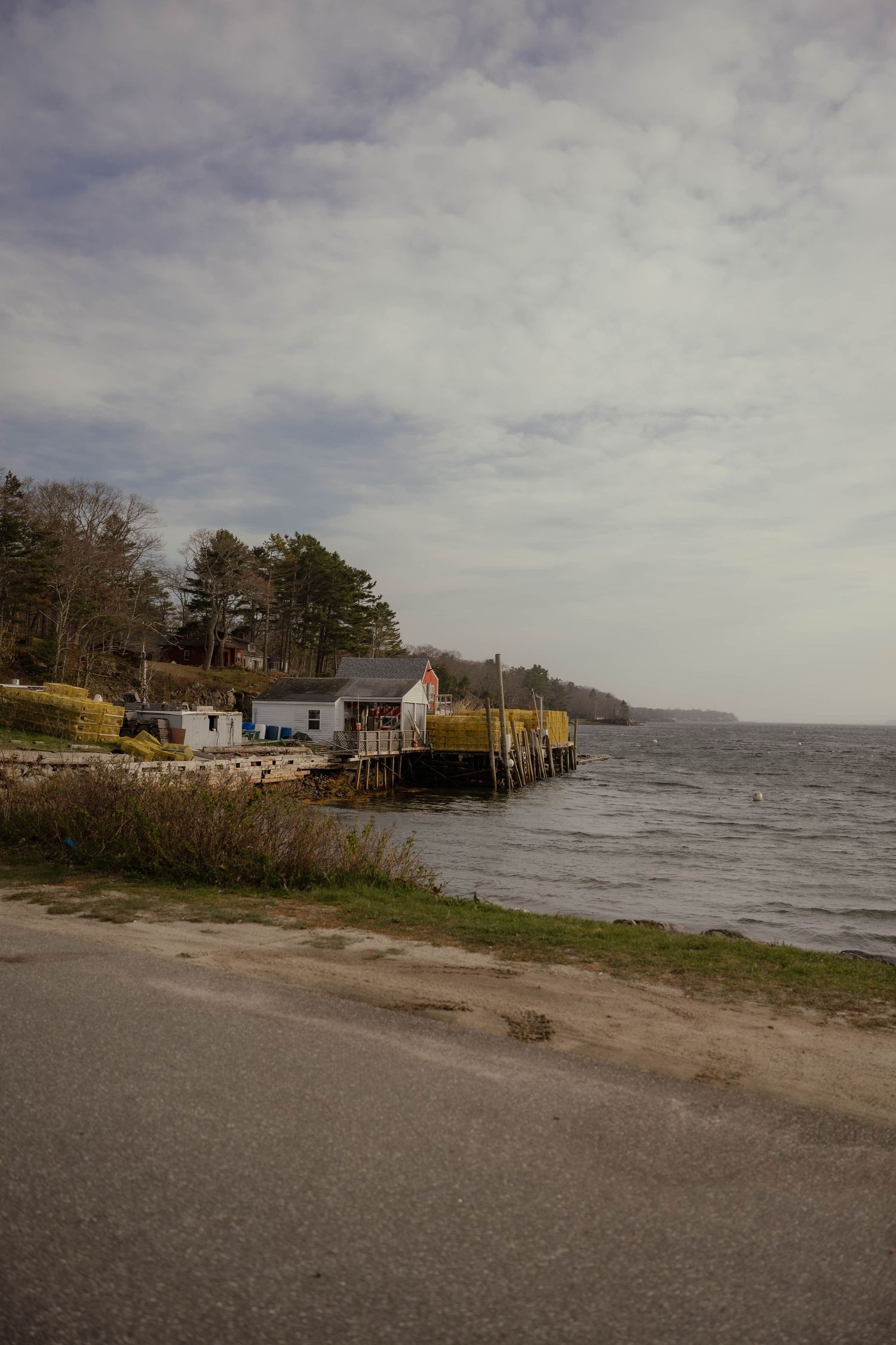 Peaceful coastal scene with a small fishing dock and buildings along a calm waterway.