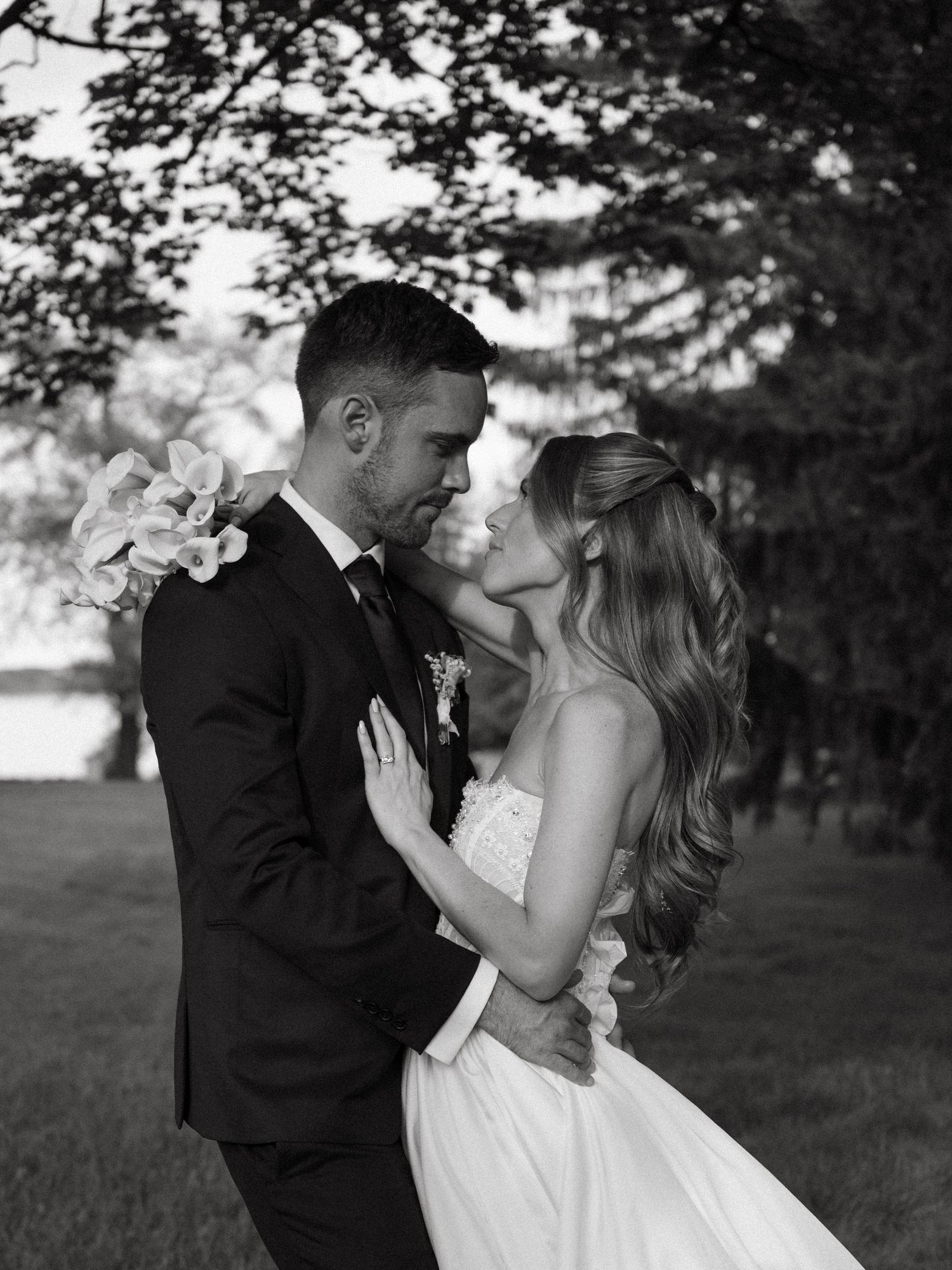 Black and white portrait of bride and groom gazing at each other in an outdoor garden setting.