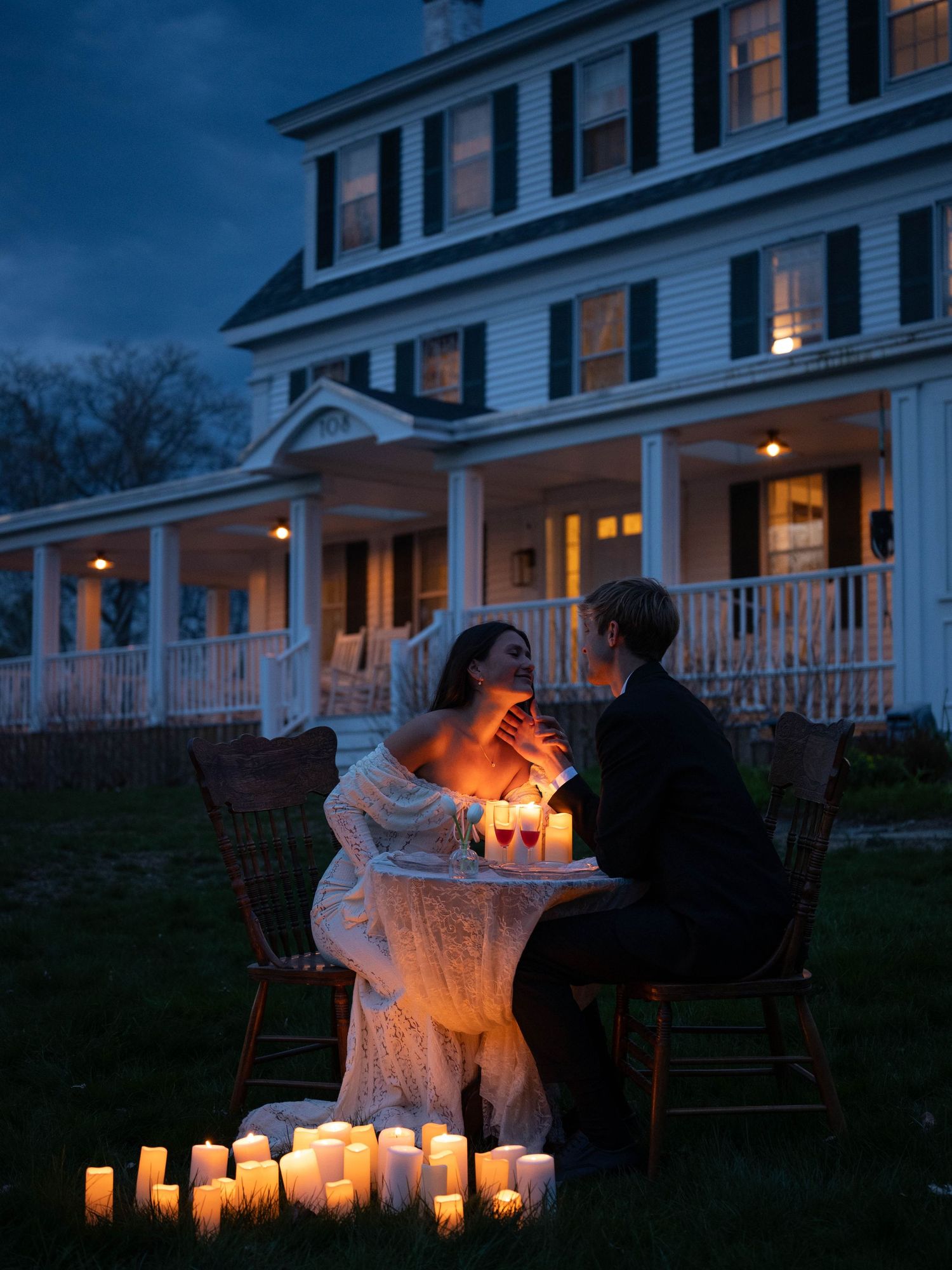 Couple shares intimate candlelit dinner outdoors at night surrounded by glowing candles.