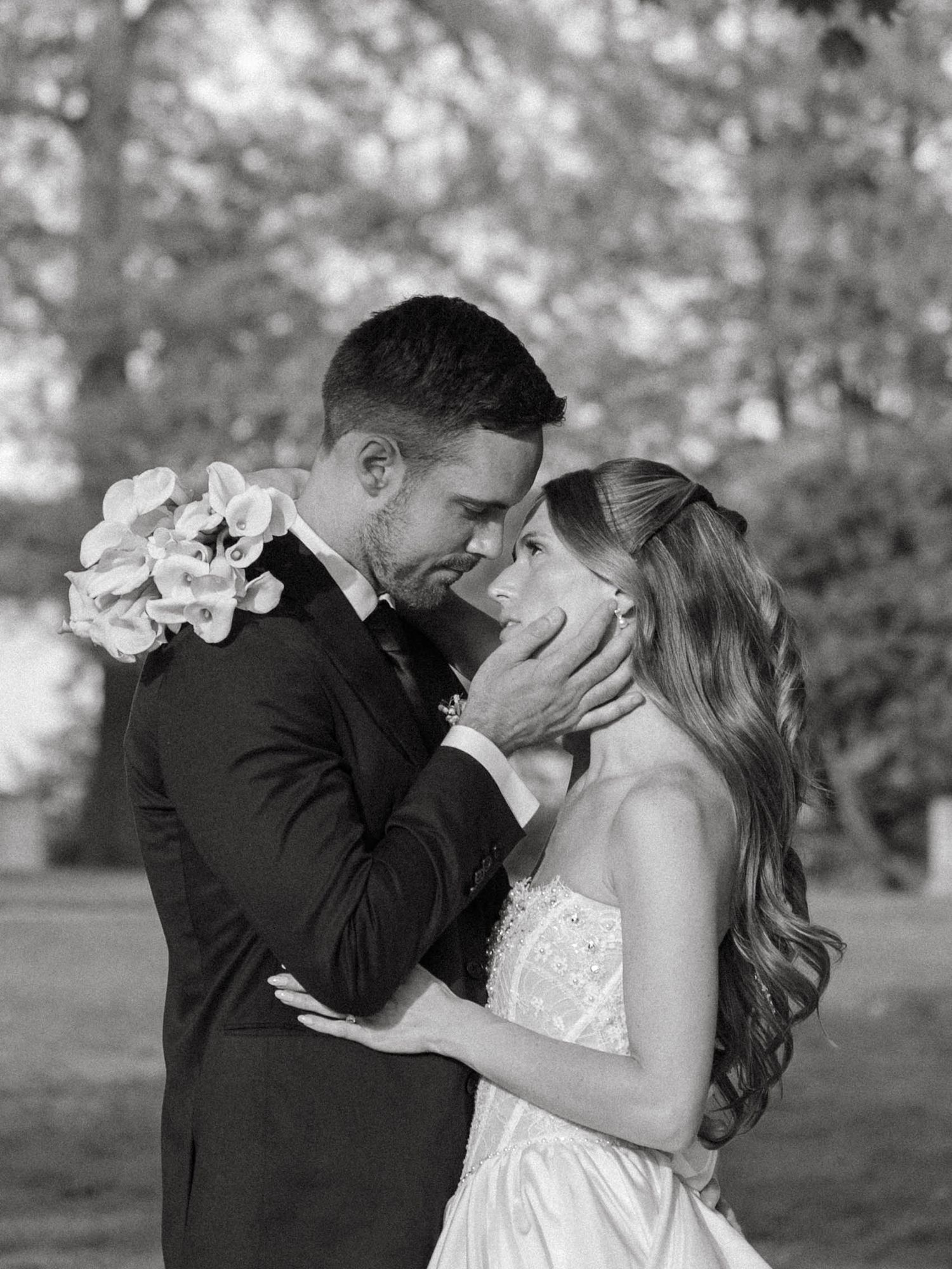 Black and white close-up of groom tenderly cupping brides face as they share an intimate moment.