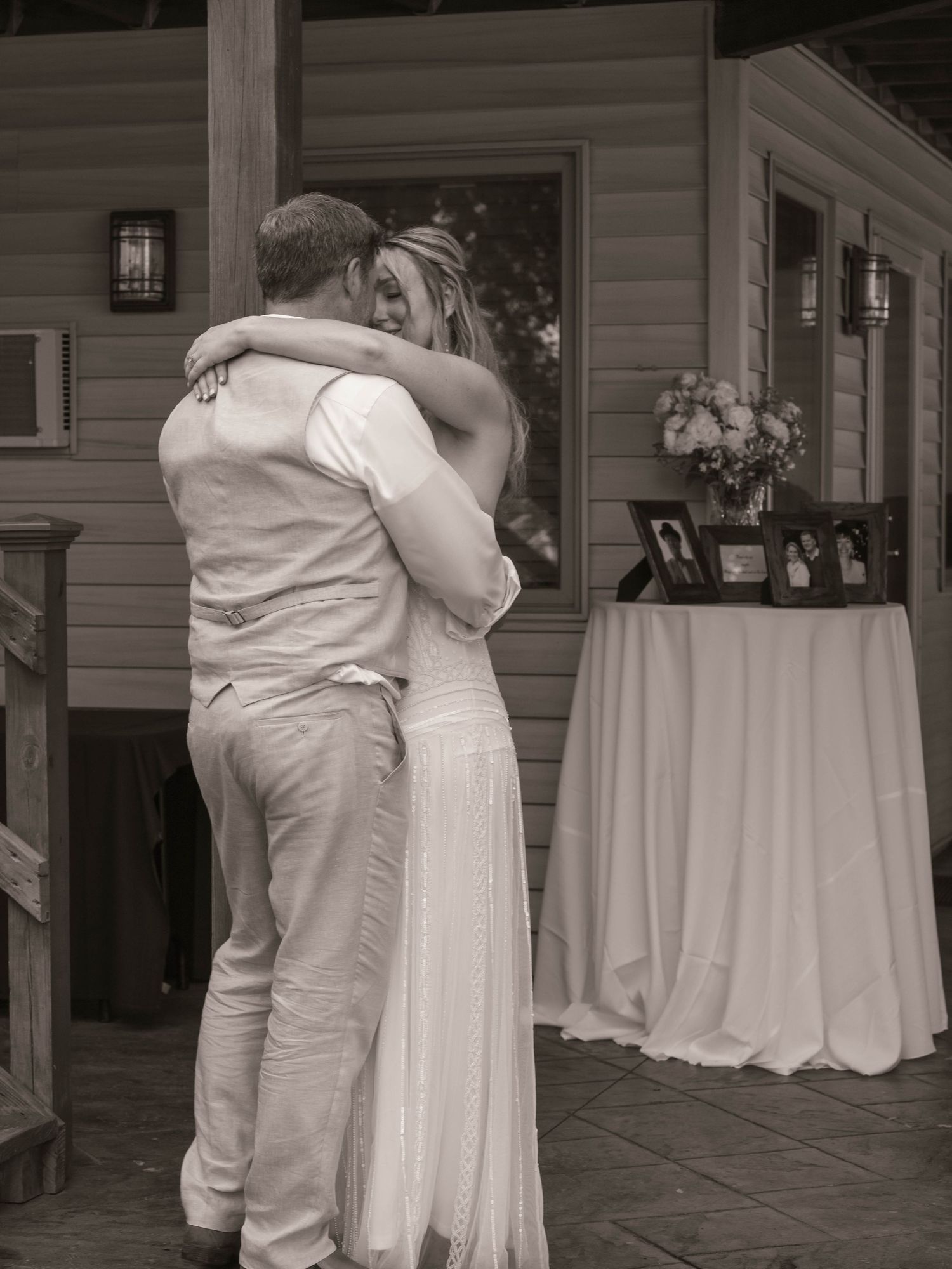 Black and white photo of a couple sharing a romantic embrace during their first dance at an outdoor wedding reception.