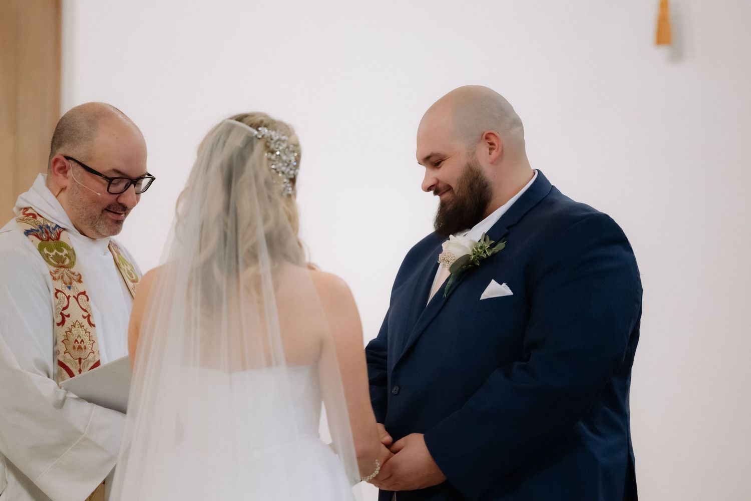 Bride and groom exchange vows at altar with officiant during intimate church wedding ceremony.