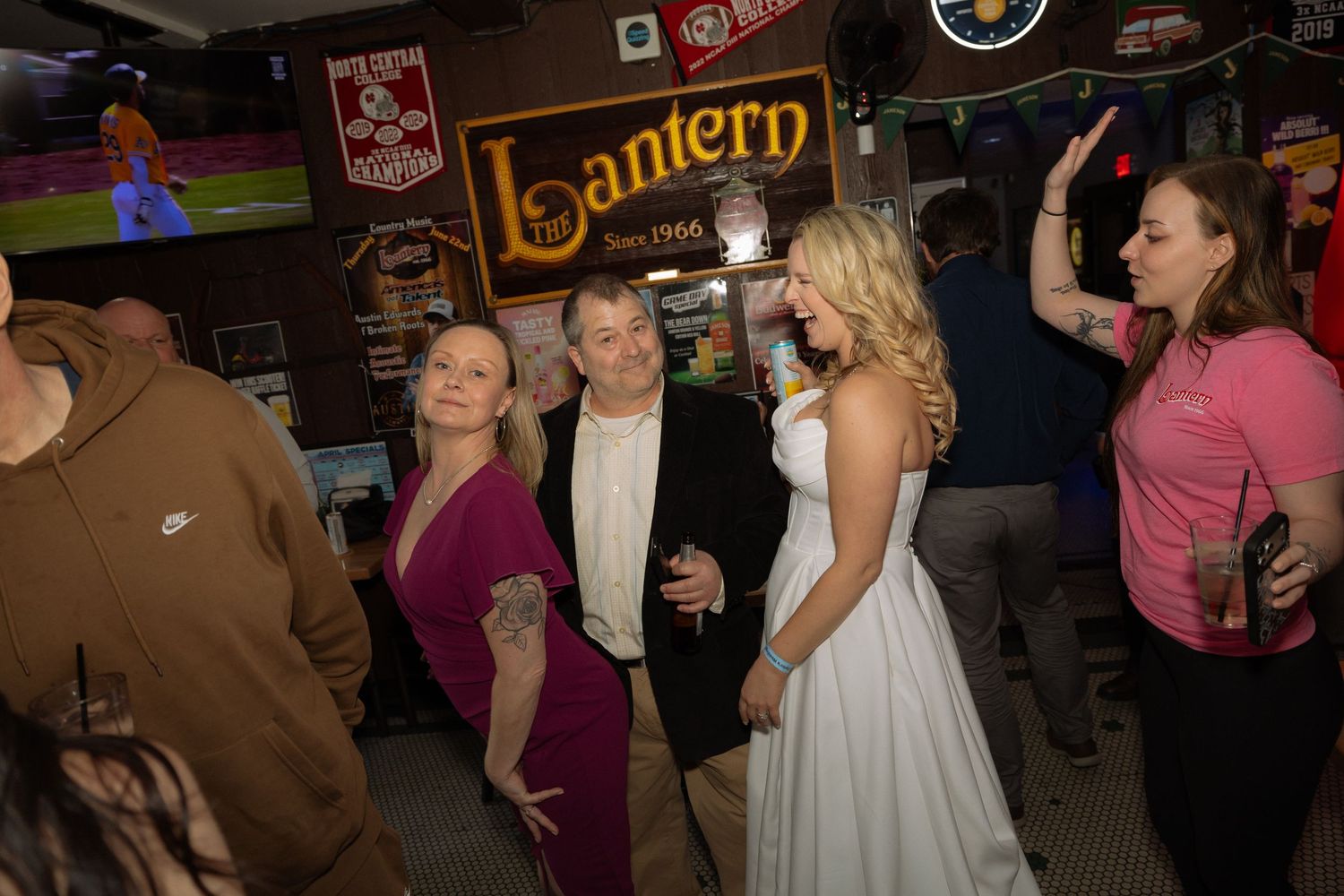 People socializing at Lantern Bar, including a woman in a wedding dress, at a lively indoor gathering.