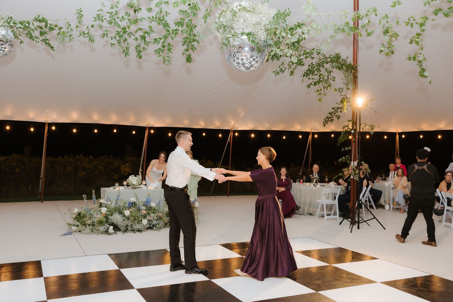 Mother and son share a special dance on a black and white checkered dance floor at a wedding.