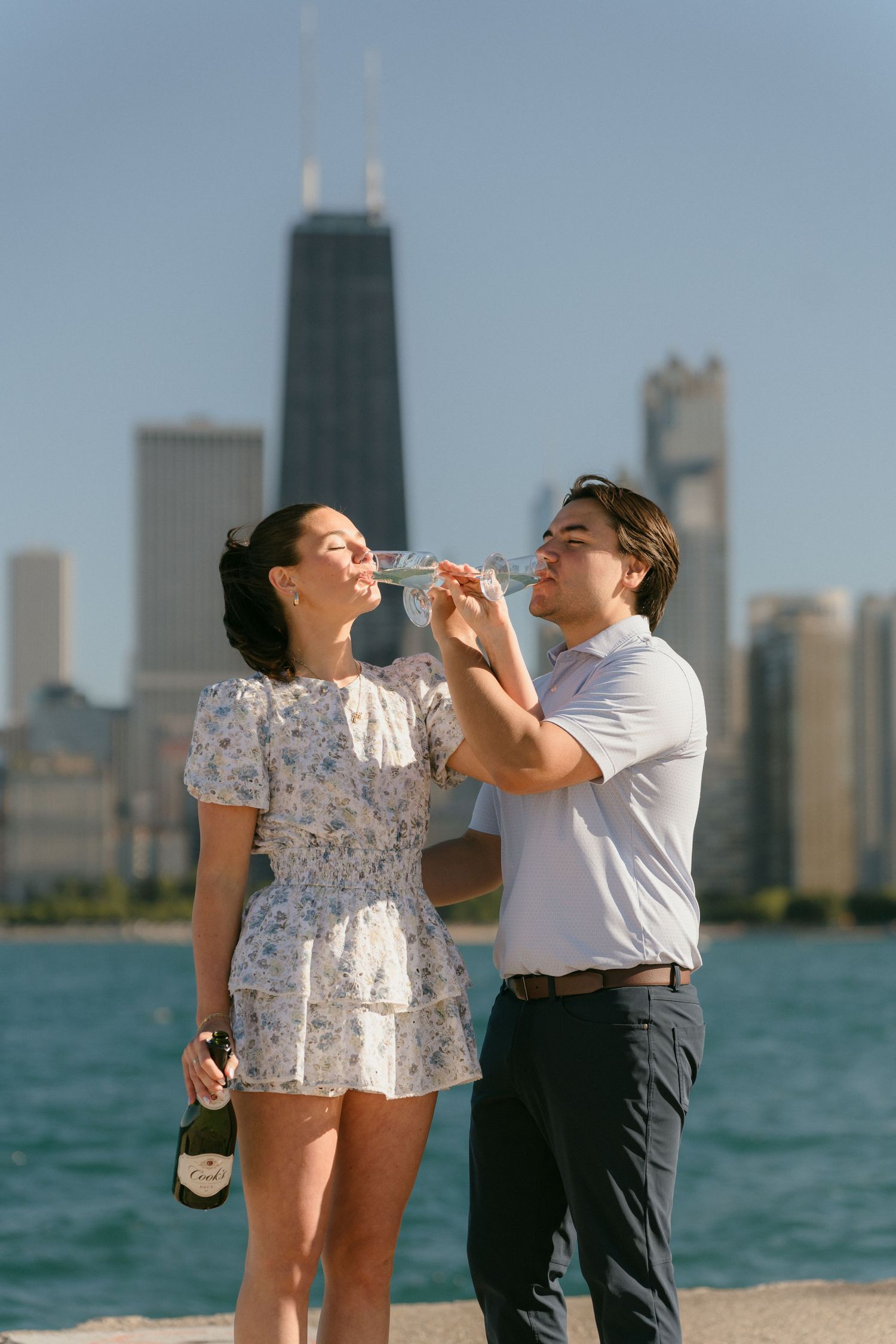 Couple drinking champagne together on Chicago lakefront with John Hancock Center in background.