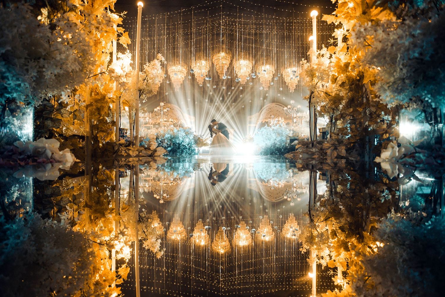 Stunning wedding venue with golden floral arches, chandelier reflections, and dramatic light rays creating a magical symmetrical scene.