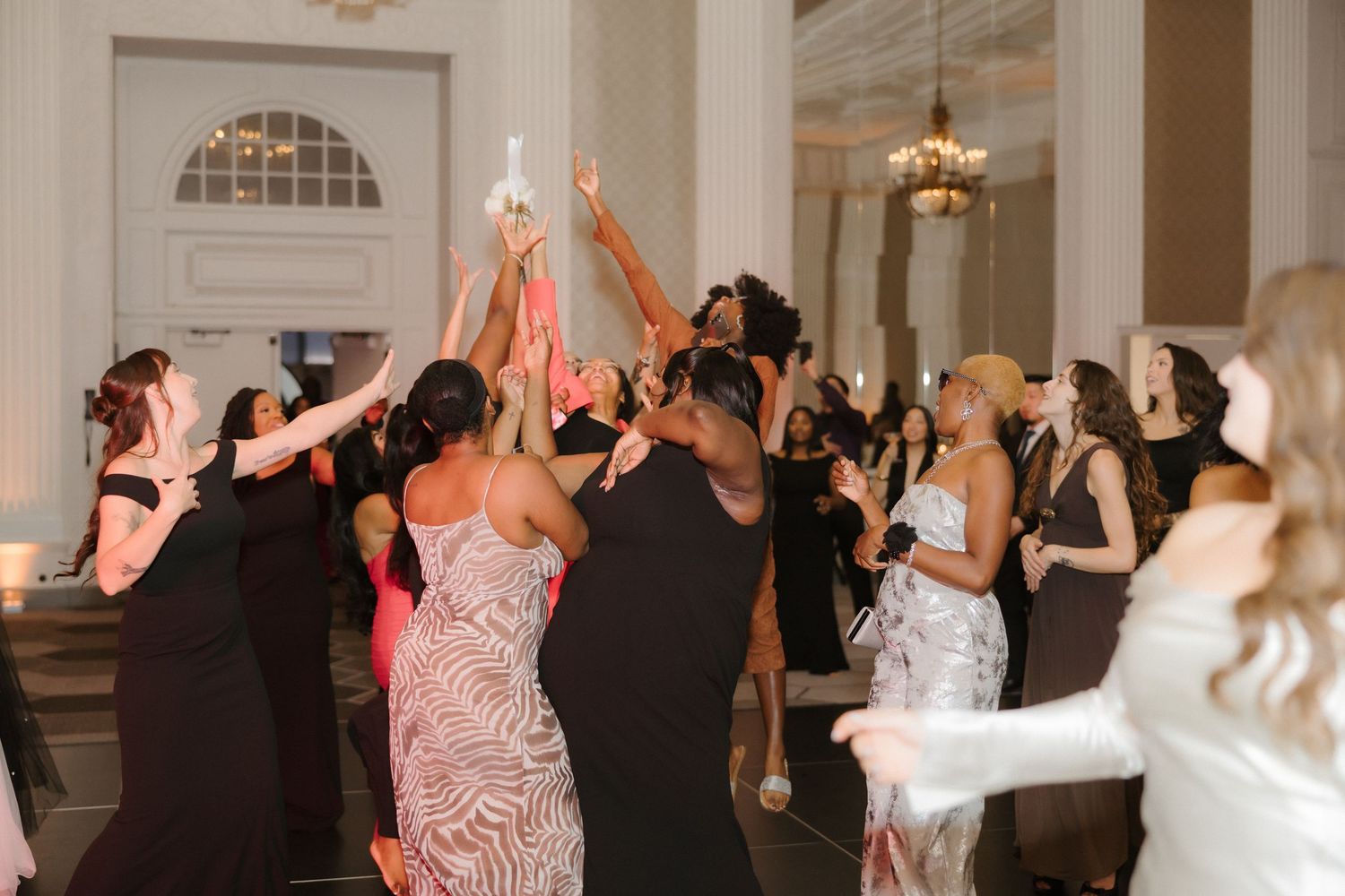 Guests dancing and celebrating at an elegant wedding reception in a grand ballroom venue.