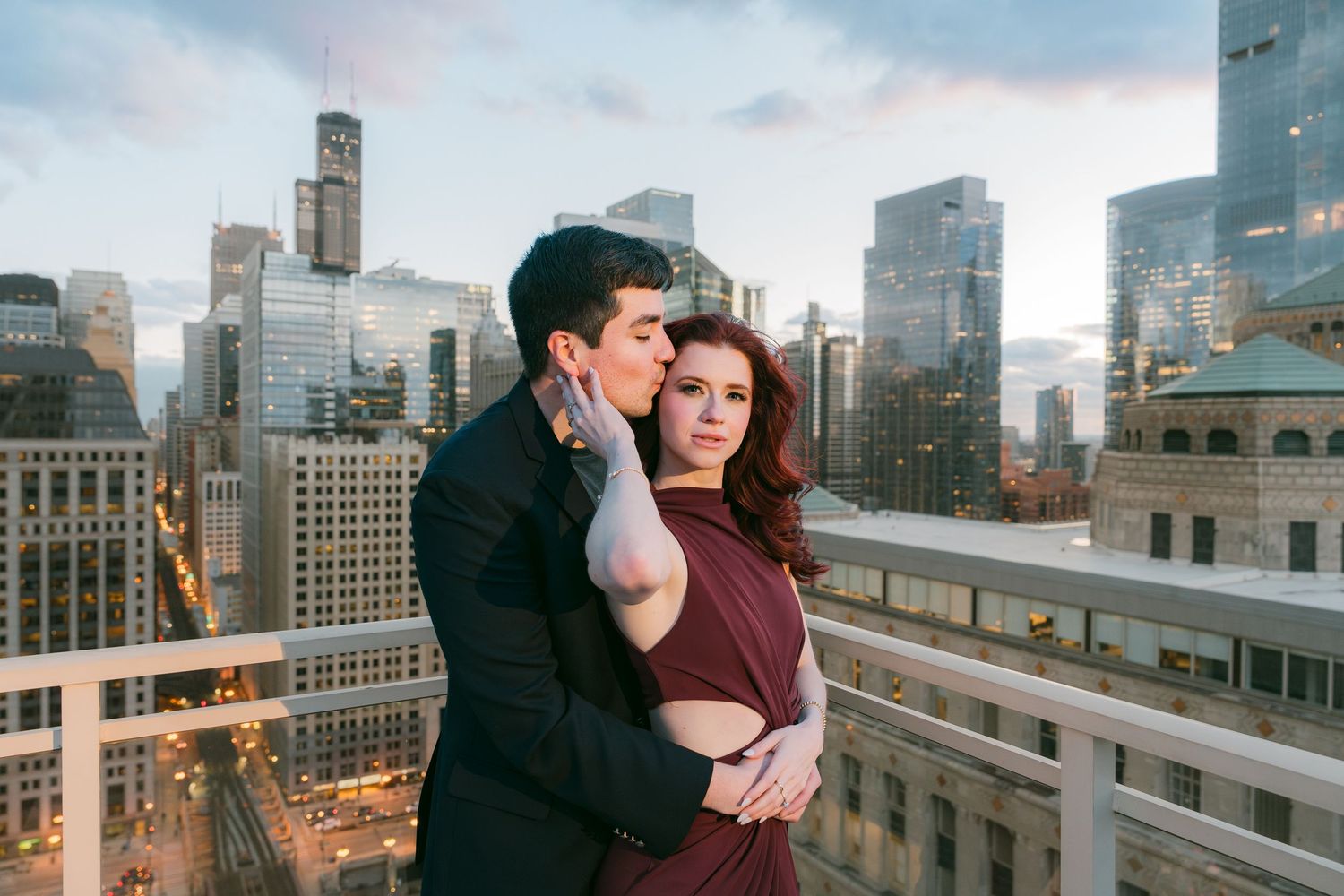 Couple in intimate embrace on Chicago rooftop with illuminated city buildings behind them.