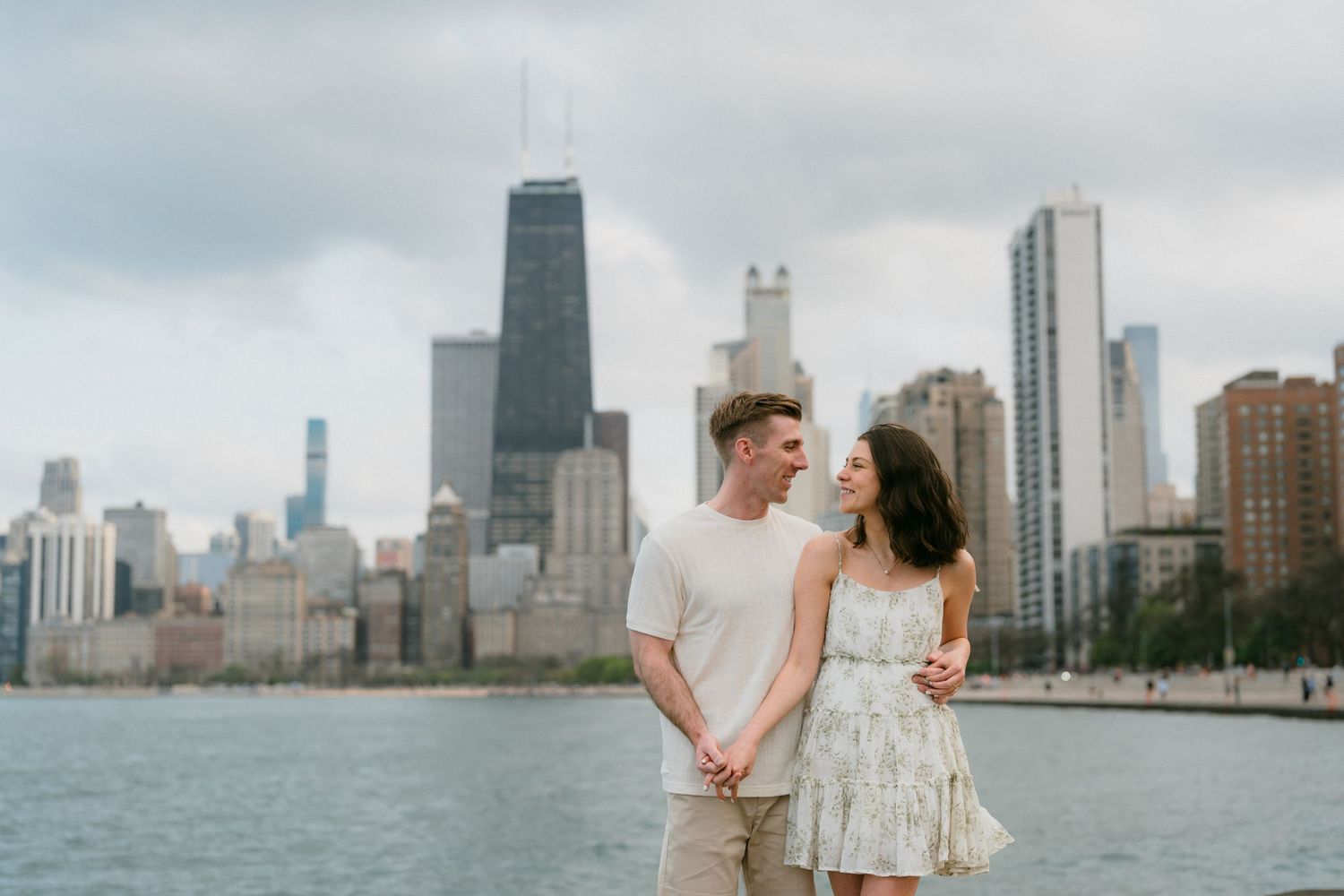 Happy couple holding hands with Chicago skyline and Lake Michigan in background.
