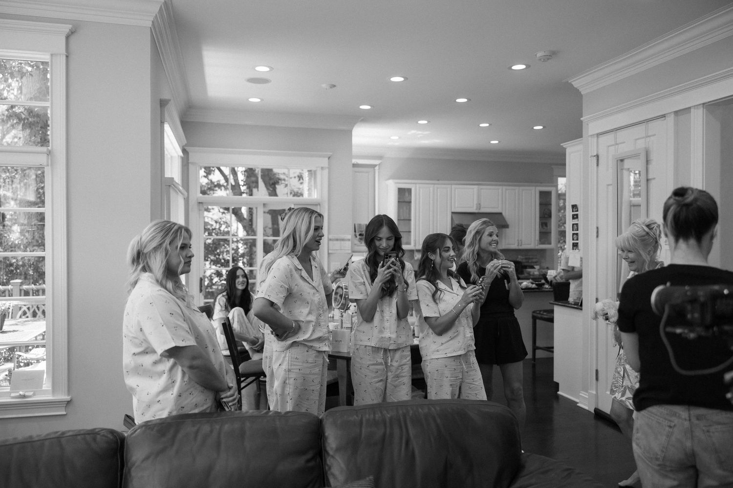 Black and white photo of a group of women gathered in a bright living room, socializing and conversing at a casual gathering.