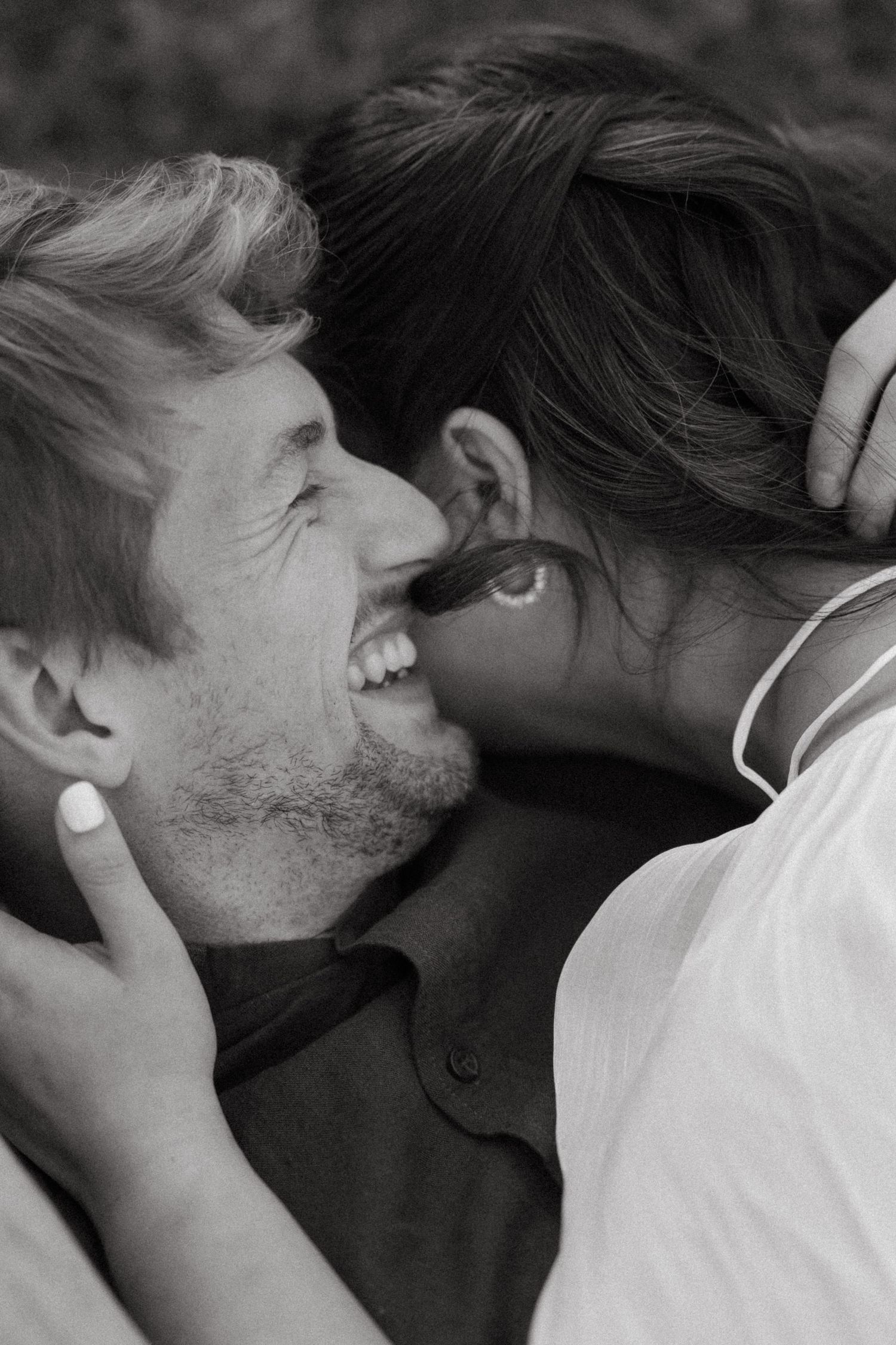 Black and white romantic close-up of smiling groom and bride sharing an intimate moment outdoors.